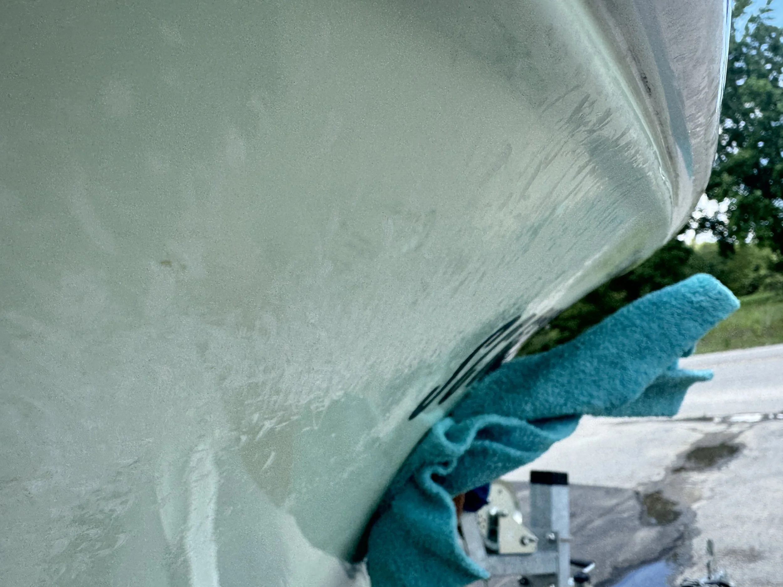 Close-up of the side of a car being washed, with a blue cloth wiping the surface.
