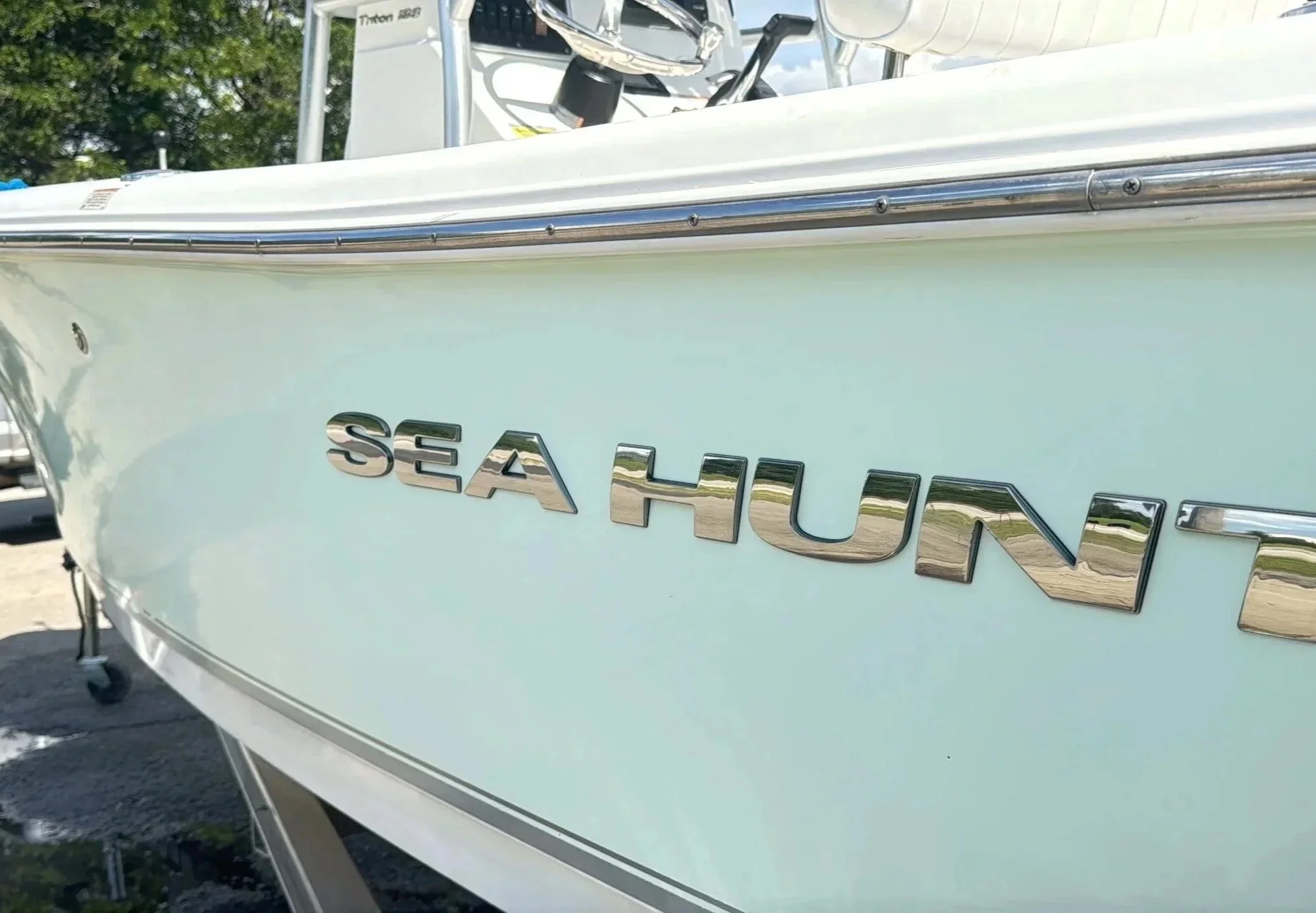 Close-up of a Sea Hunt boat's side with chrome lettering on light-colored hull