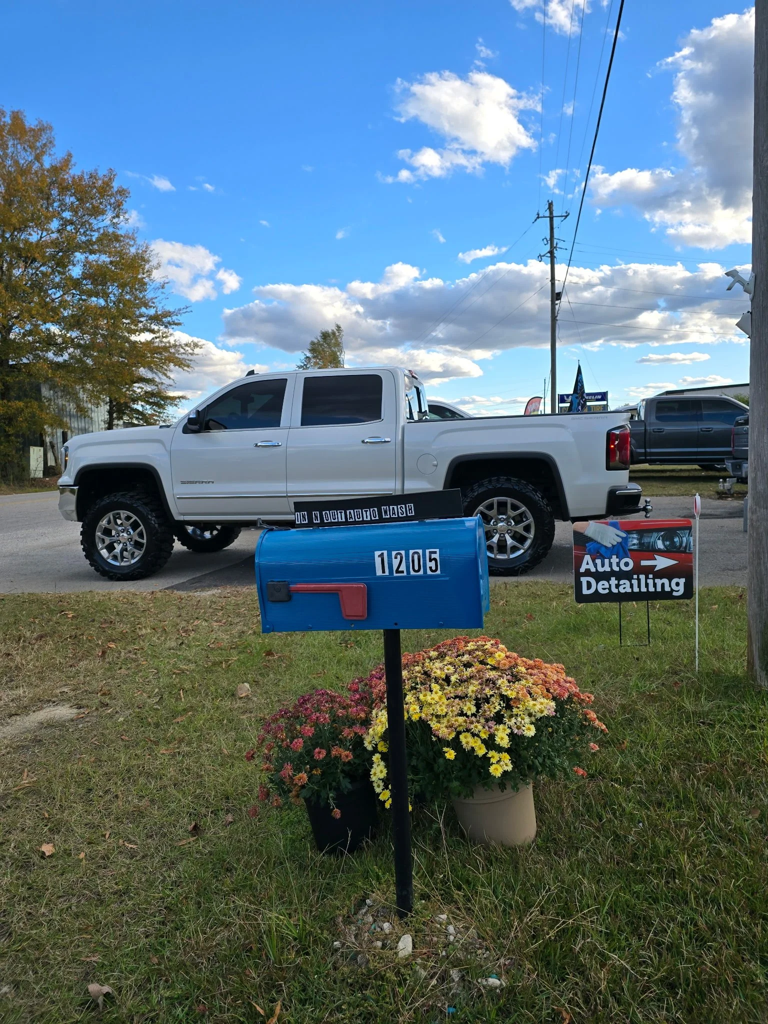 A white pickup truck parked outside an auto detailing shop with signs advertising auto detailing services. Gtechniq  5 year ceramic coating 