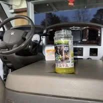 Inside a vehicle, a container of dietary supplement pills labeled 'Super Cleanse' is placed on the dashboard in front of the steering wheel.