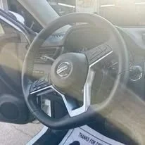Close-up of a car steering wheel with a Mercedes-Benz logo, taken from the driver's perspective.