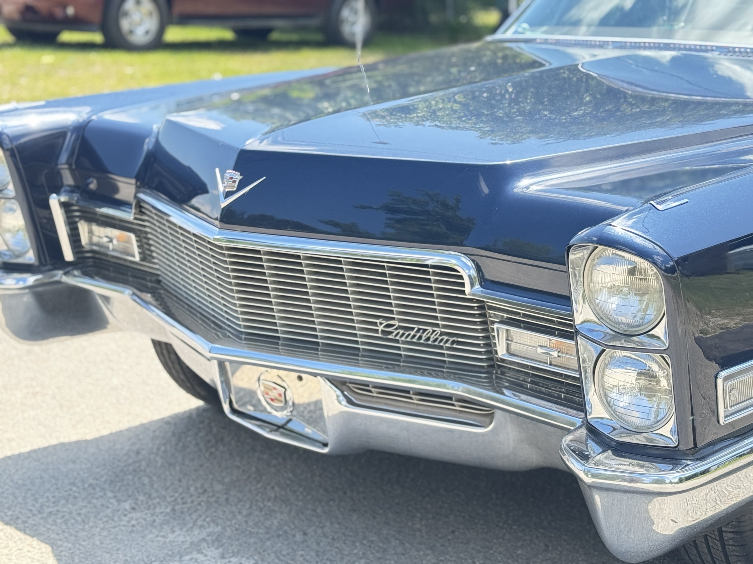 Front view of a vintage blue Cadillac car with chrome details, grille, and headlight design.