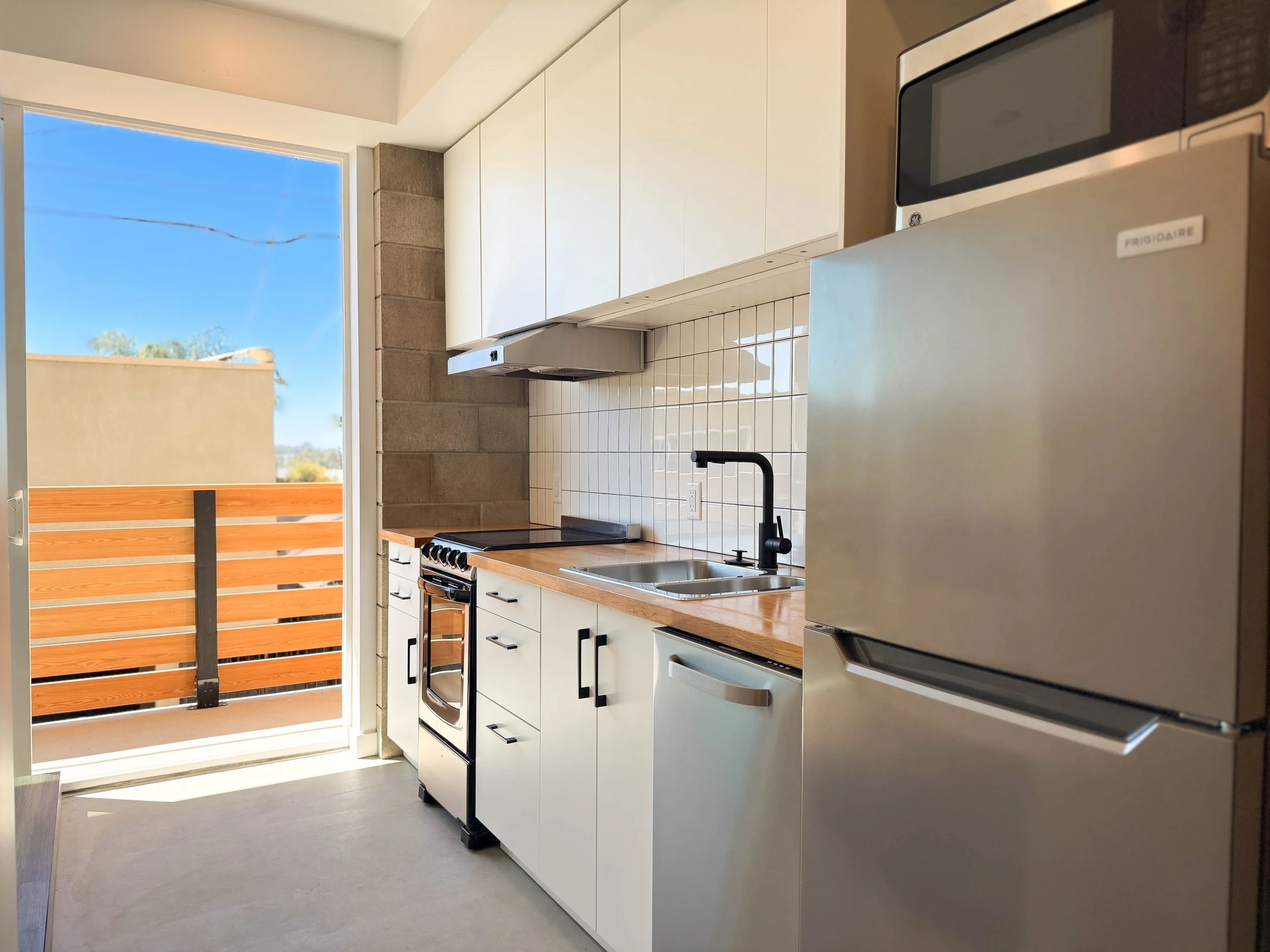 Floor plan of a small apartment with a bedroom, bathroom, kitchen, and balcony with two chairs and a small table.