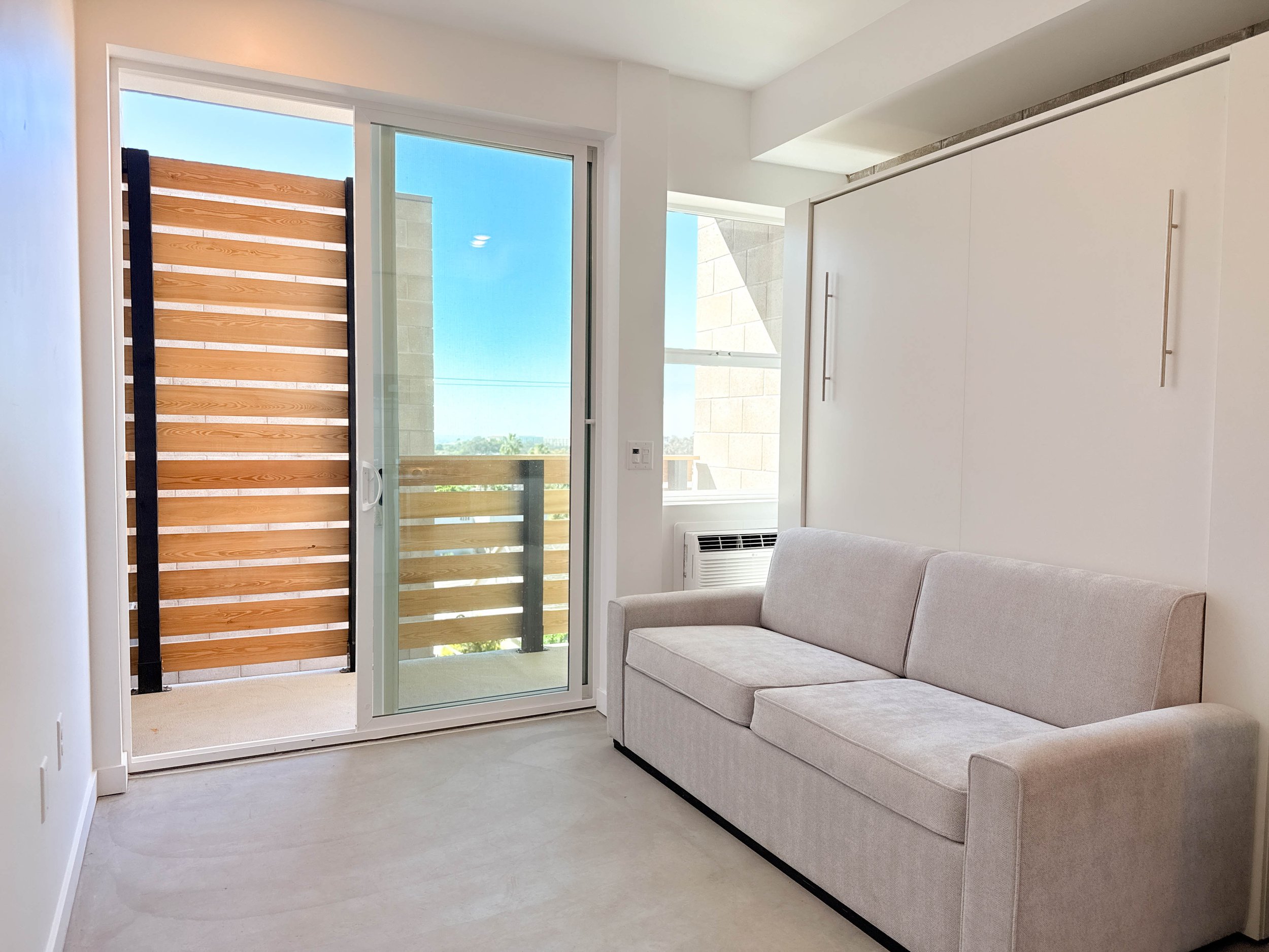 Floor plan of a small apartment with a bedroom, bathroom, kitchen, and balcony with two chairs and a small table.