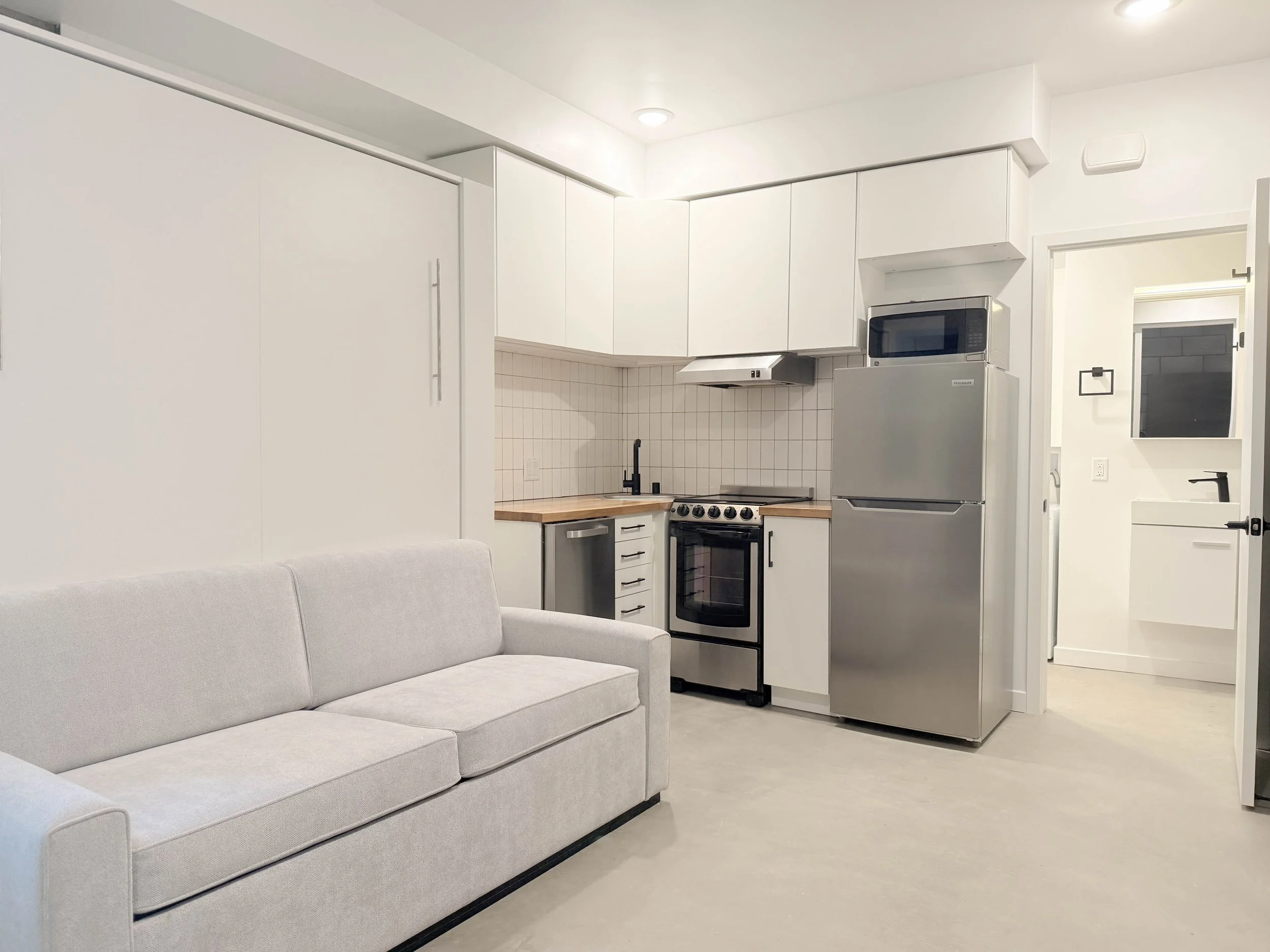 Floor plan of a small apartment with a bedroom, bathroom, kitchen, and balcony with two chairs and a small table.