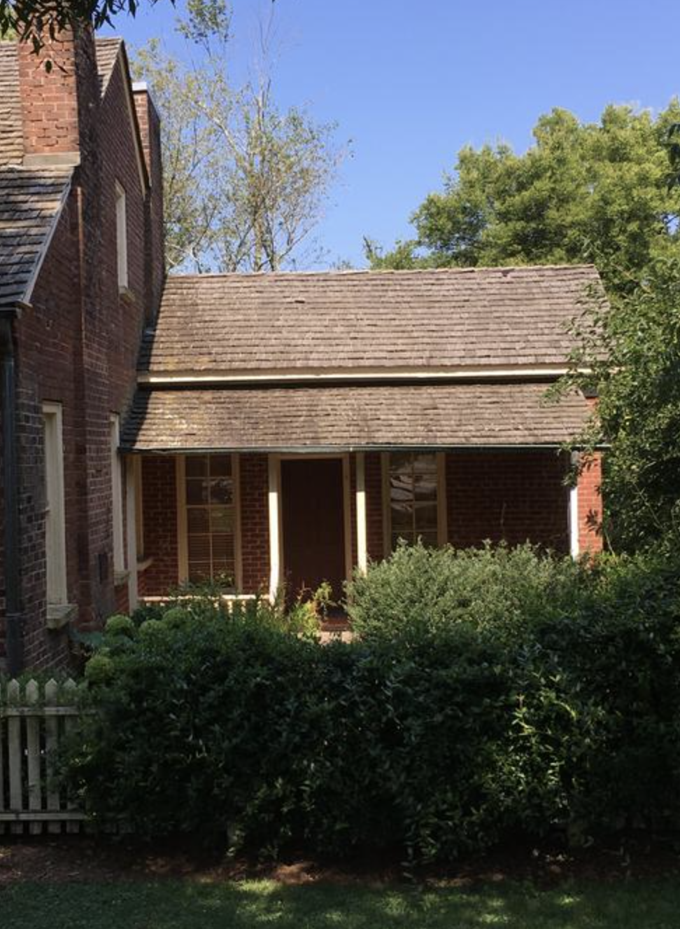 A brick house with a front porch and a garden with bushes.