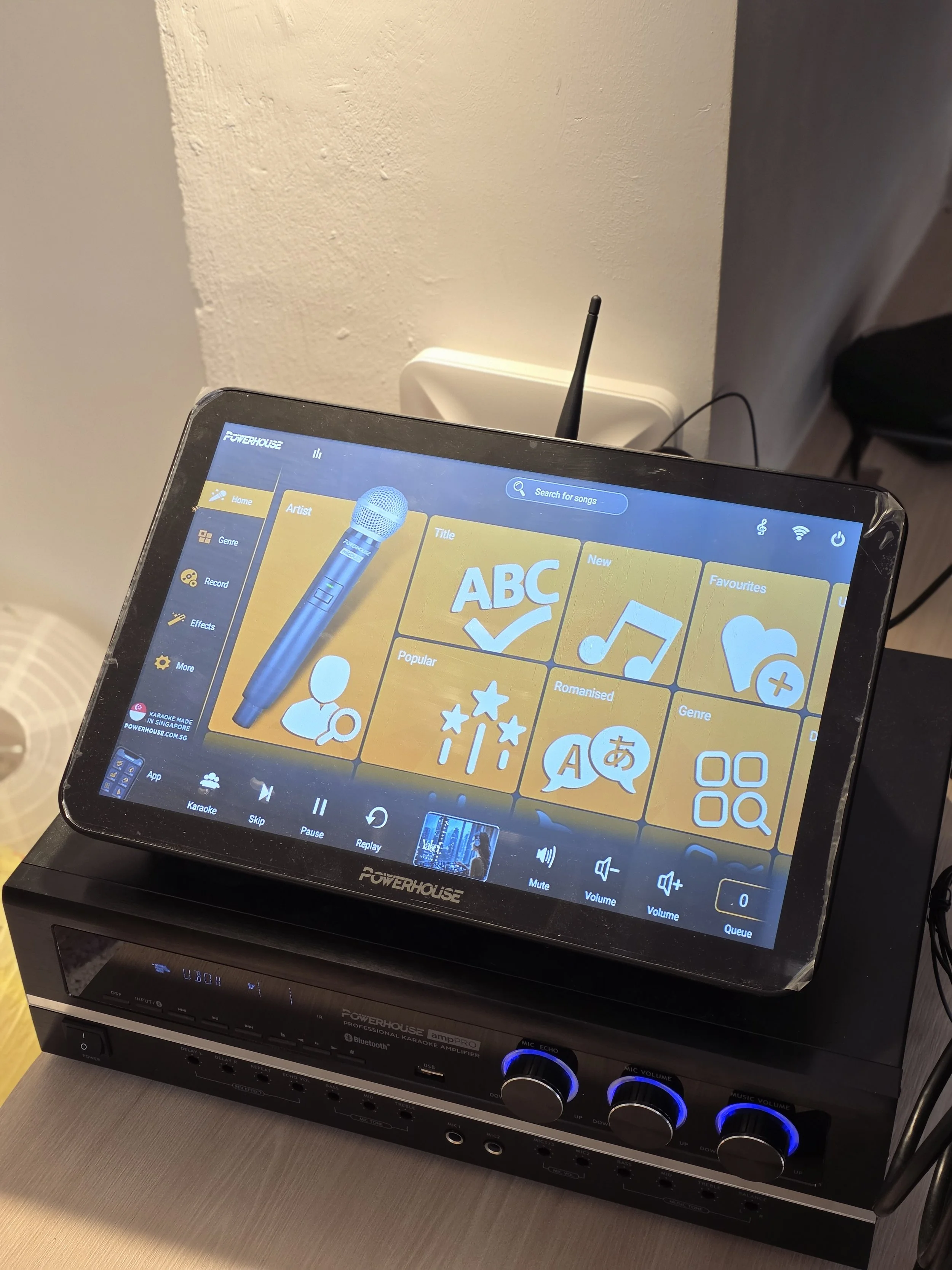The Space Grid - PA & karaoke system with a touchscreen display showing song selection options, placed on top of an amplifier with control knobs.