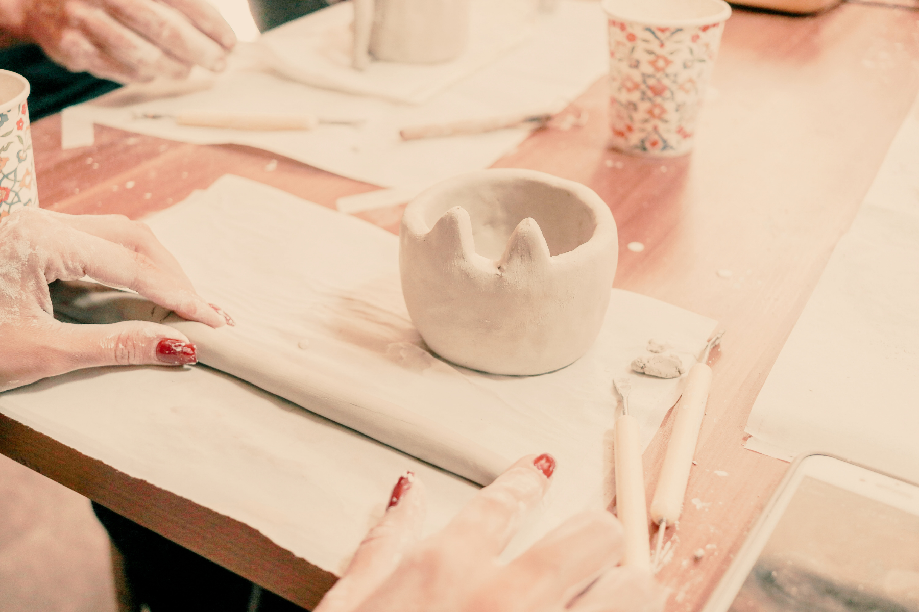 hands rolling sculpting clay on a table