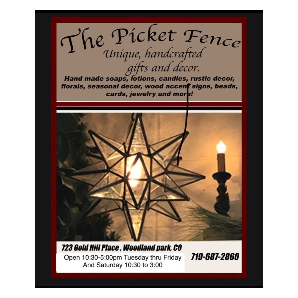 A decorated showcase sign for The Picket Fence store, featuring handcrafted gifts, decor, and seasonal items. The sign includes a photo of a geometric star-shaped ornament and a candle, along with the store's address, contact number, and hours of operation.
