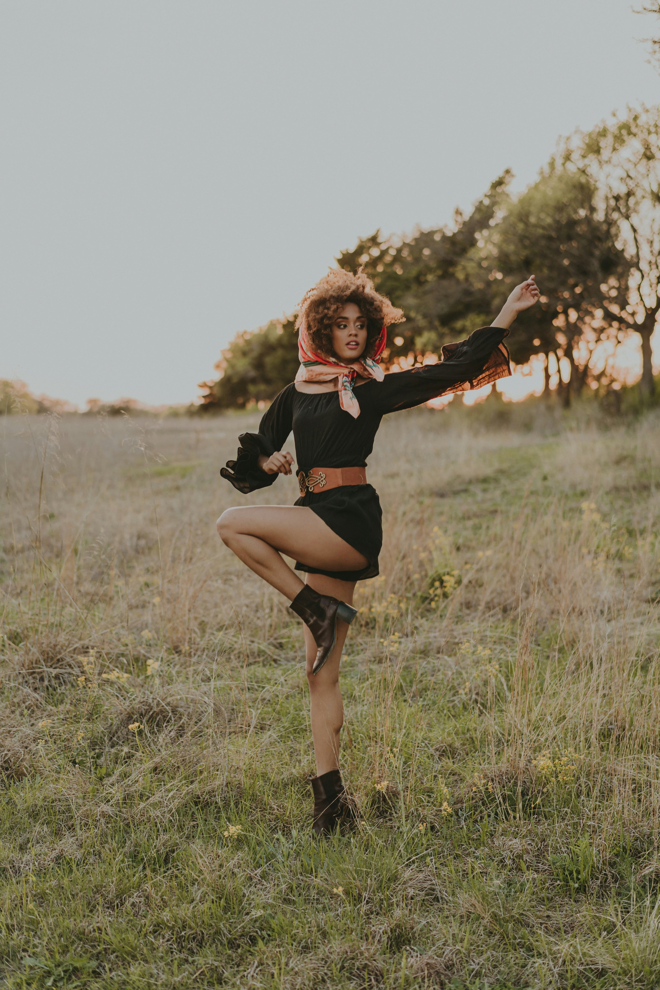 A woman with curly hair dancing in nature embracing the flow of life and nature