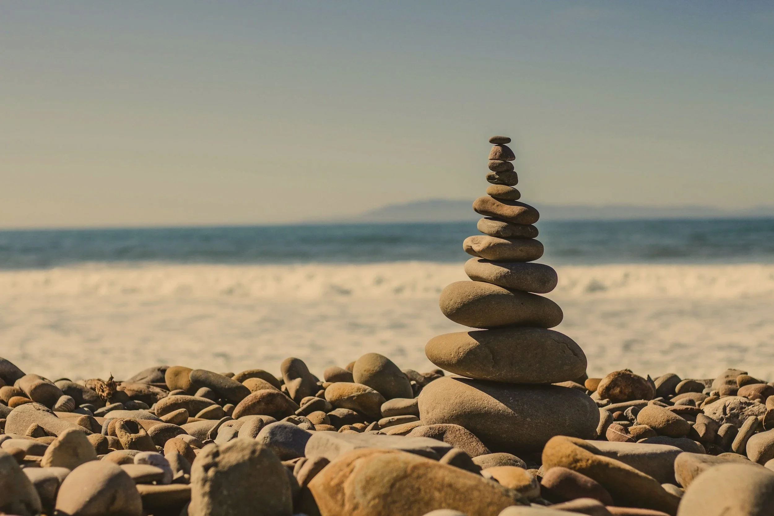 Stacked rocks on a beach with the ocean in the background.