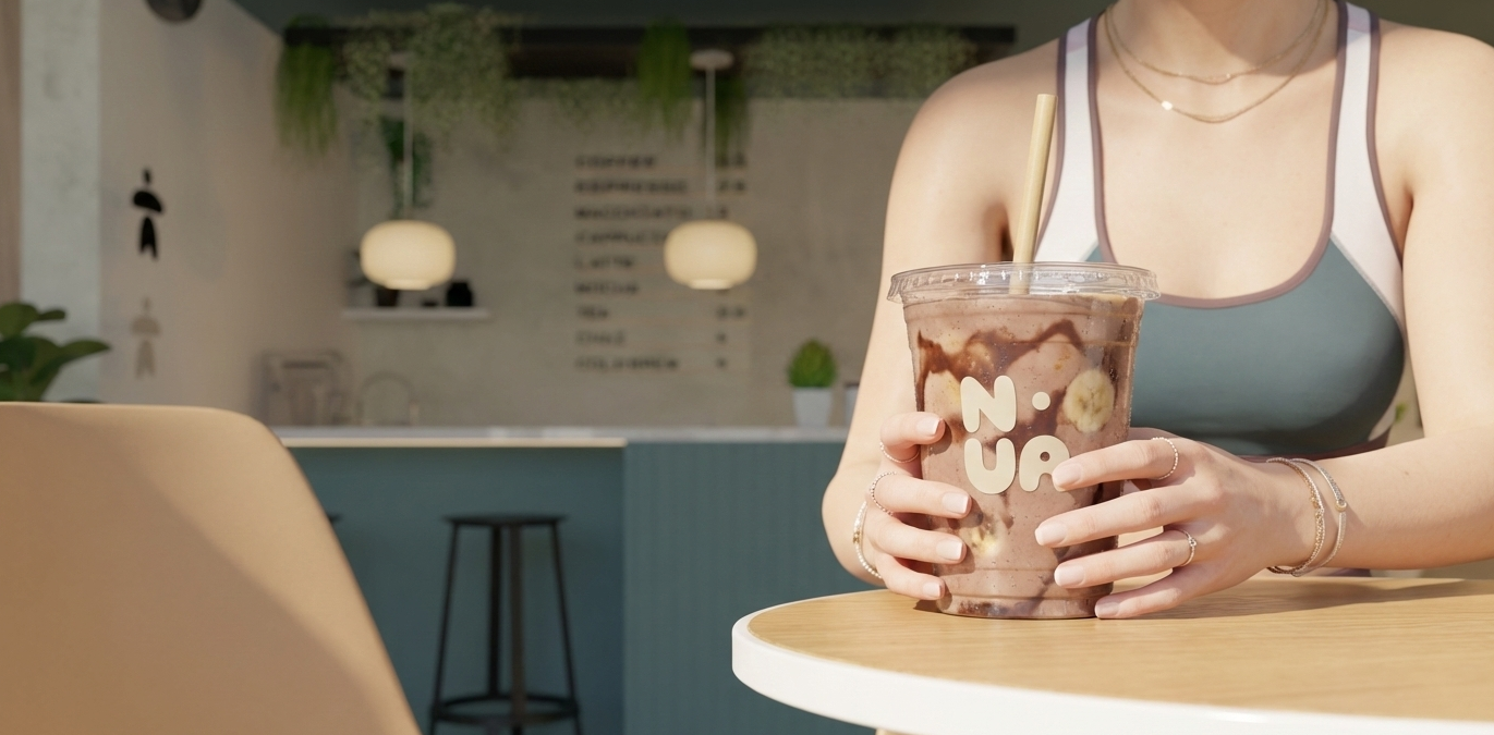 Persona sosteniendo un vaso grande con bebida de chocolate con plátano y trozos de cereal.