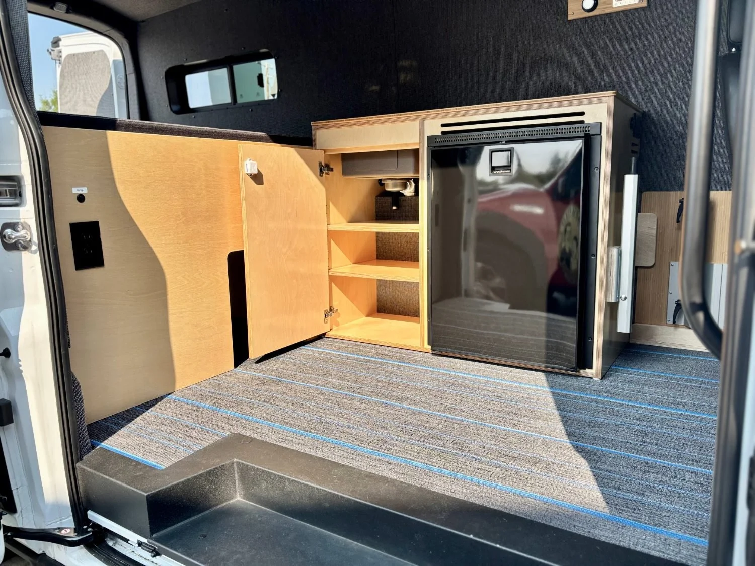 custom camper van built with galley cabinet, bed platform, flooring, wall panels and upholstery