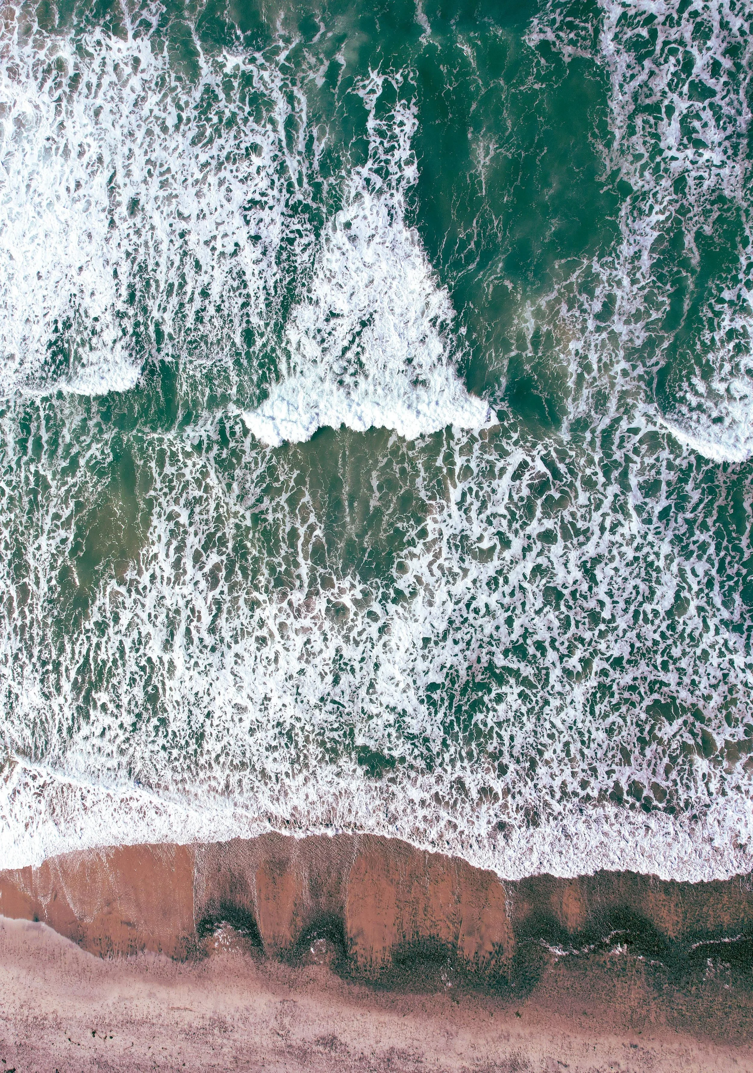 Ocean waves crashing against a red shore