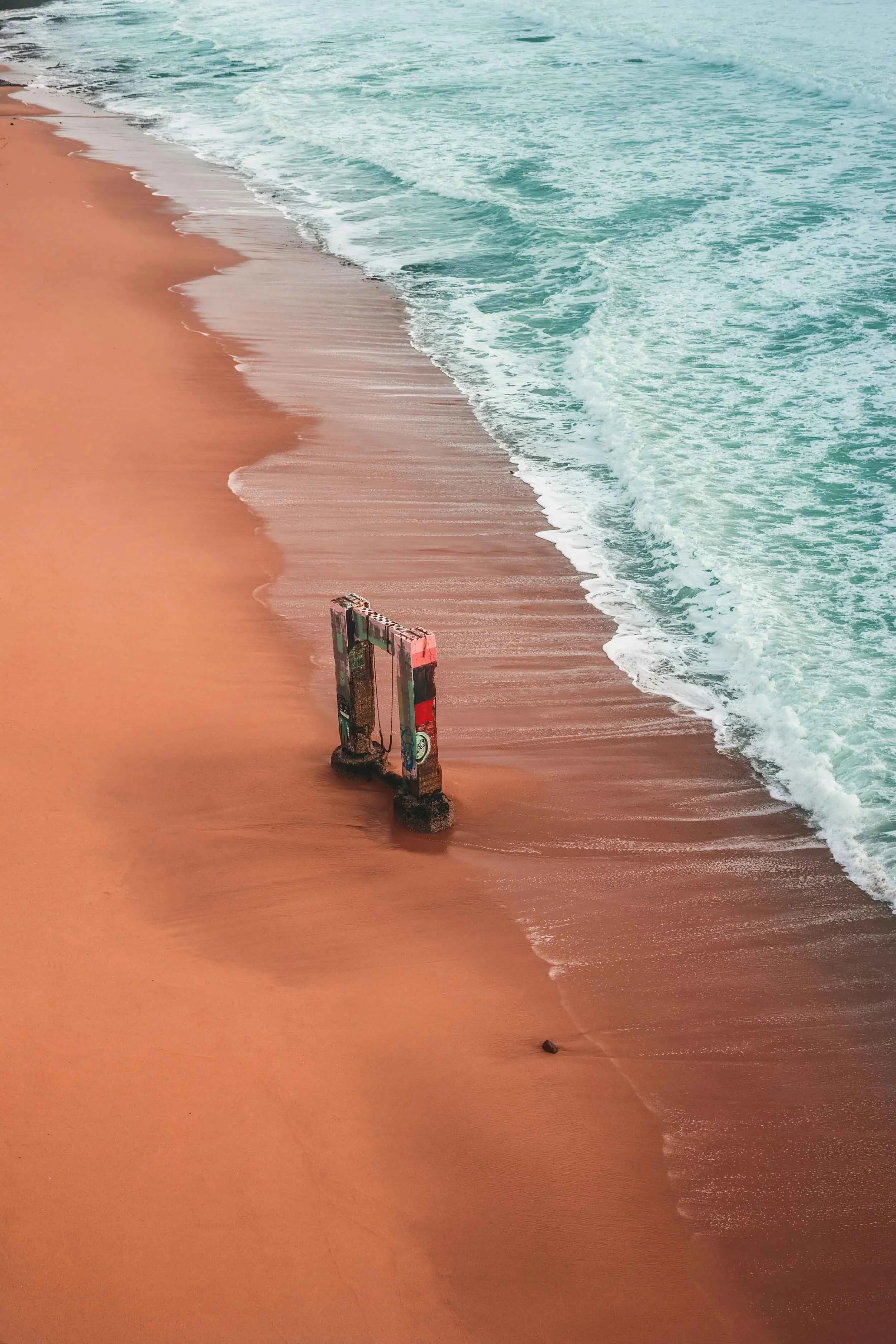 A structure on the sand with waves crashing on the shore