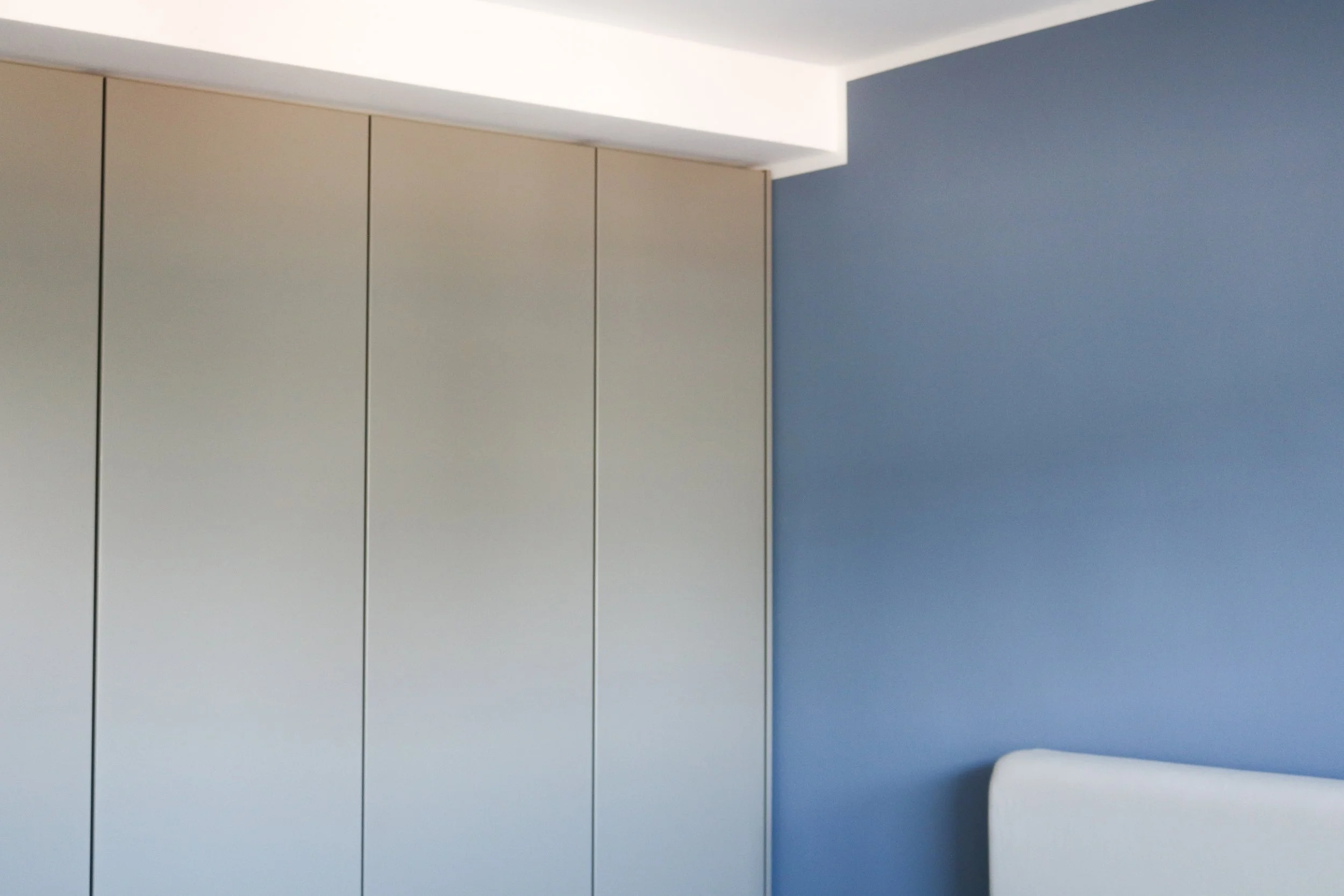 Ein Raum mit weißen Schränken an einer Wand und einer blauen Wand daneben.