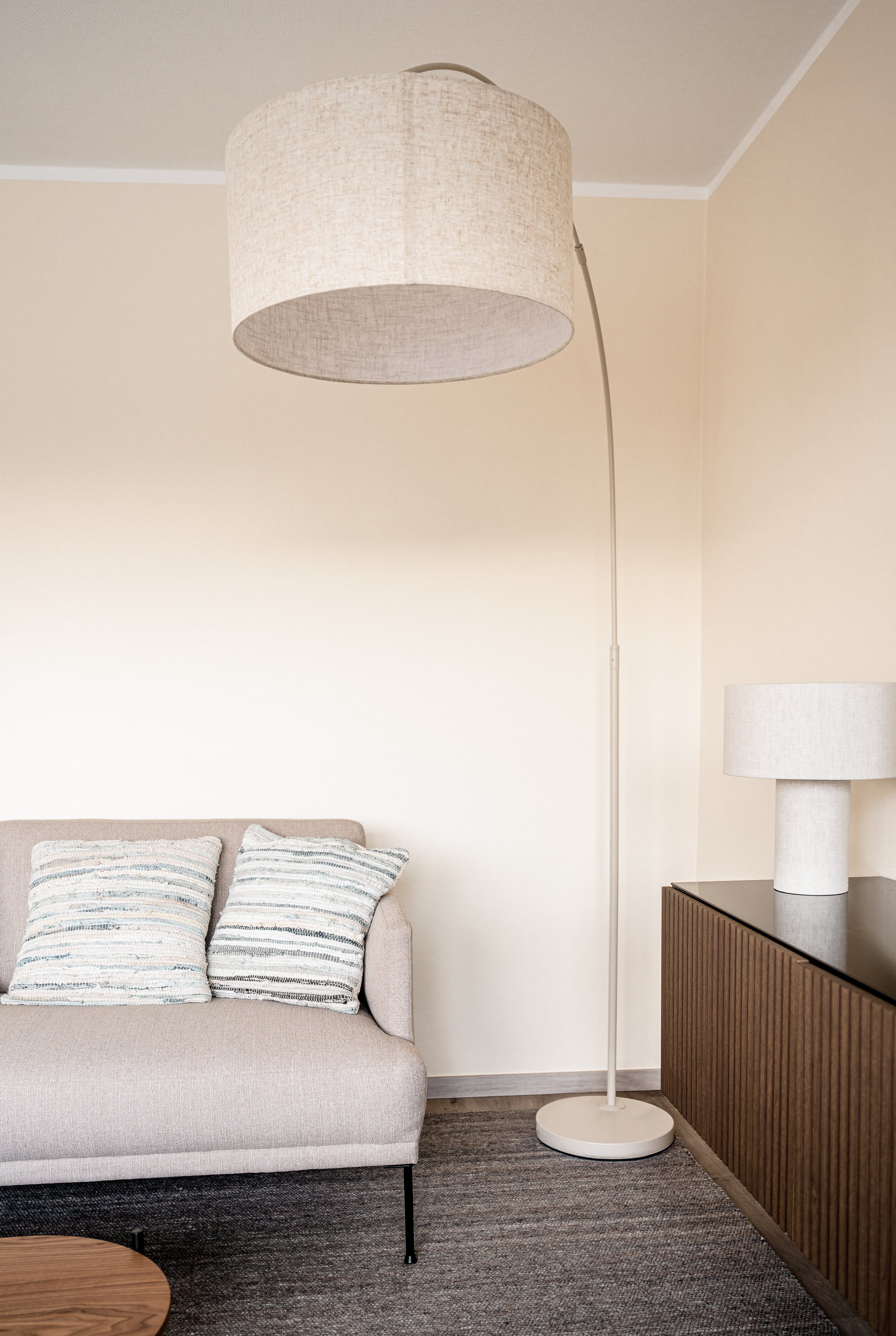 Wohnzimmer mit Sofa, Stehlampe und Sideboard.