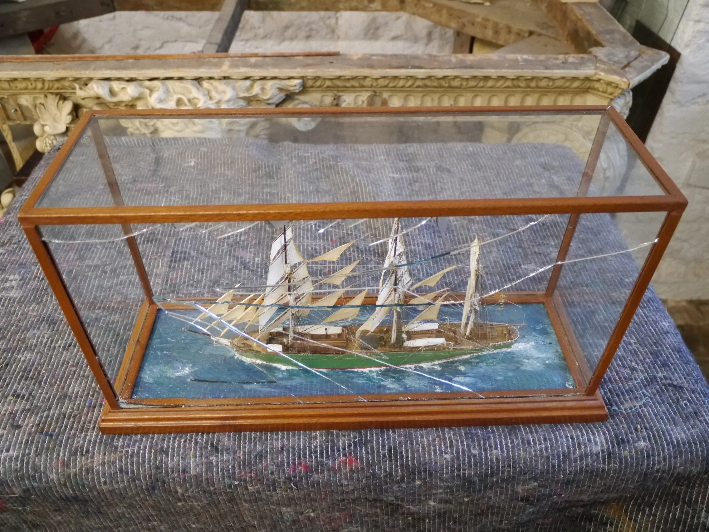 Broken glass case and vintage model ship