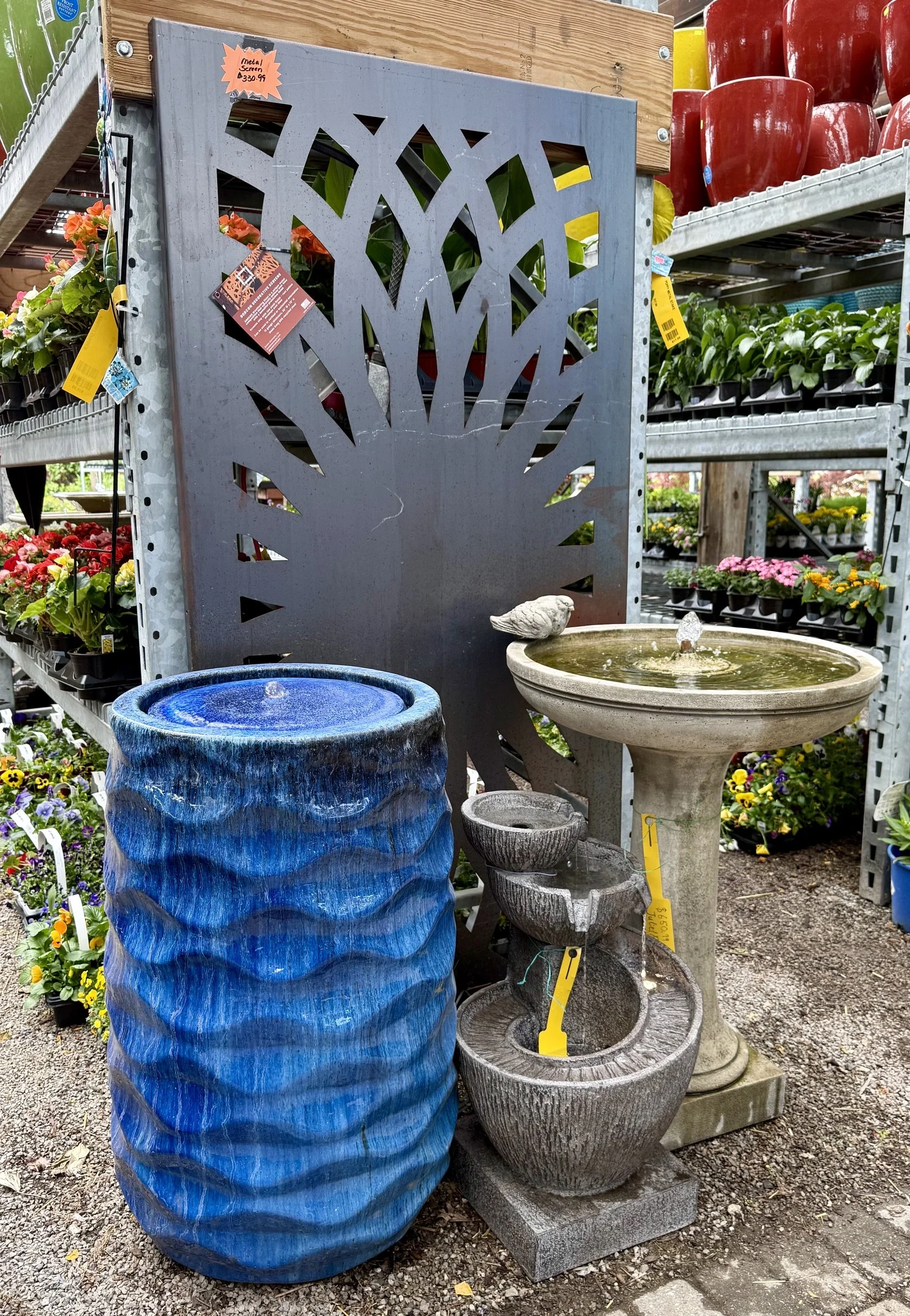 A large blue textured ceramic fountain, a tiered stone fountain with bird ornaments, and a birdbath with a bird figurine at Allemon’s Landscape Center, Detroit, Michigan serving the Grosse Pointe, St. Clair Shores, and Detroit Communities since 1929.