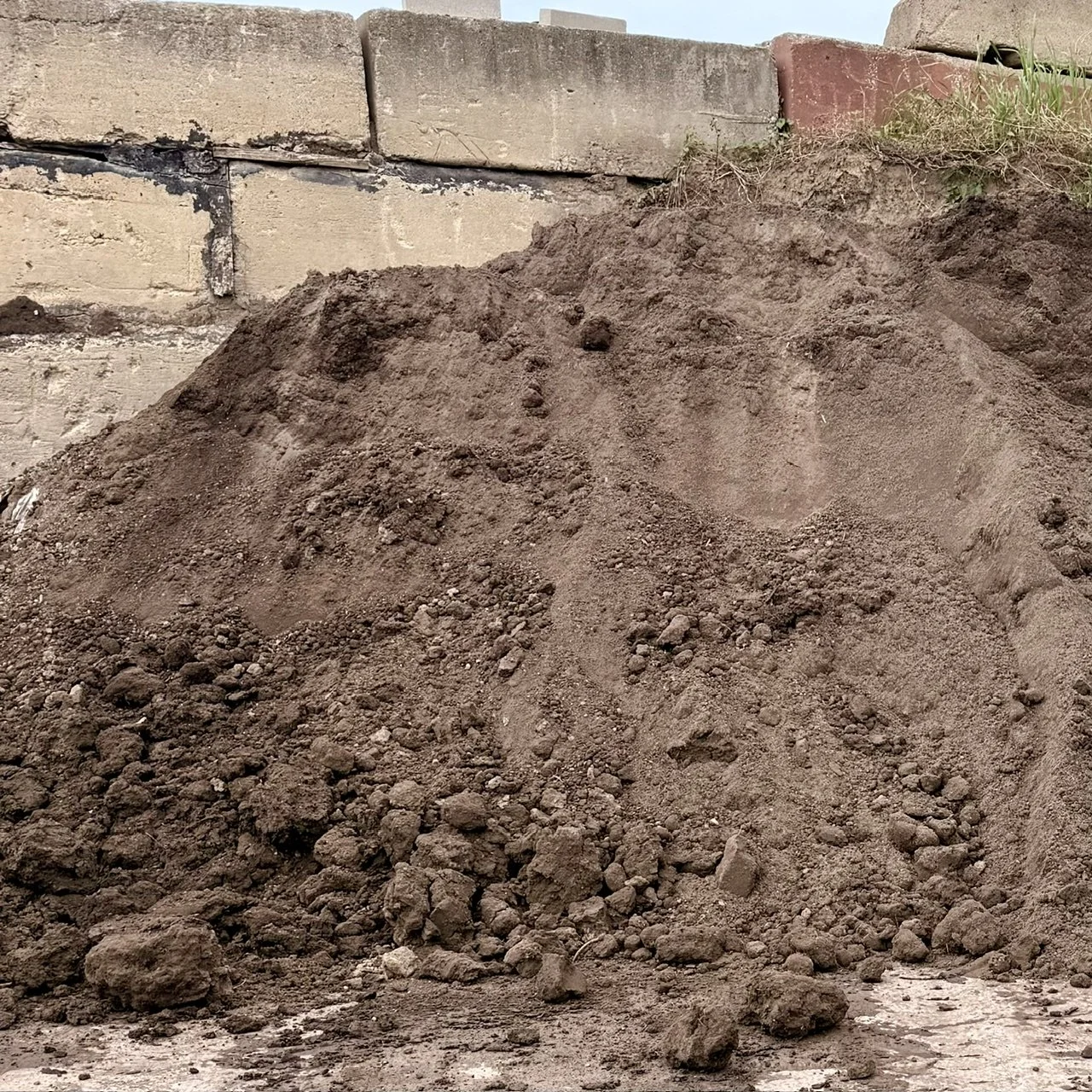 A pile of top soil in front of a concrete wall at Allemon’s Landscape Center, Detroit, Michigan serving the Grosse Pointe, St. Clair Shores, and Detroit Communities since 1929.