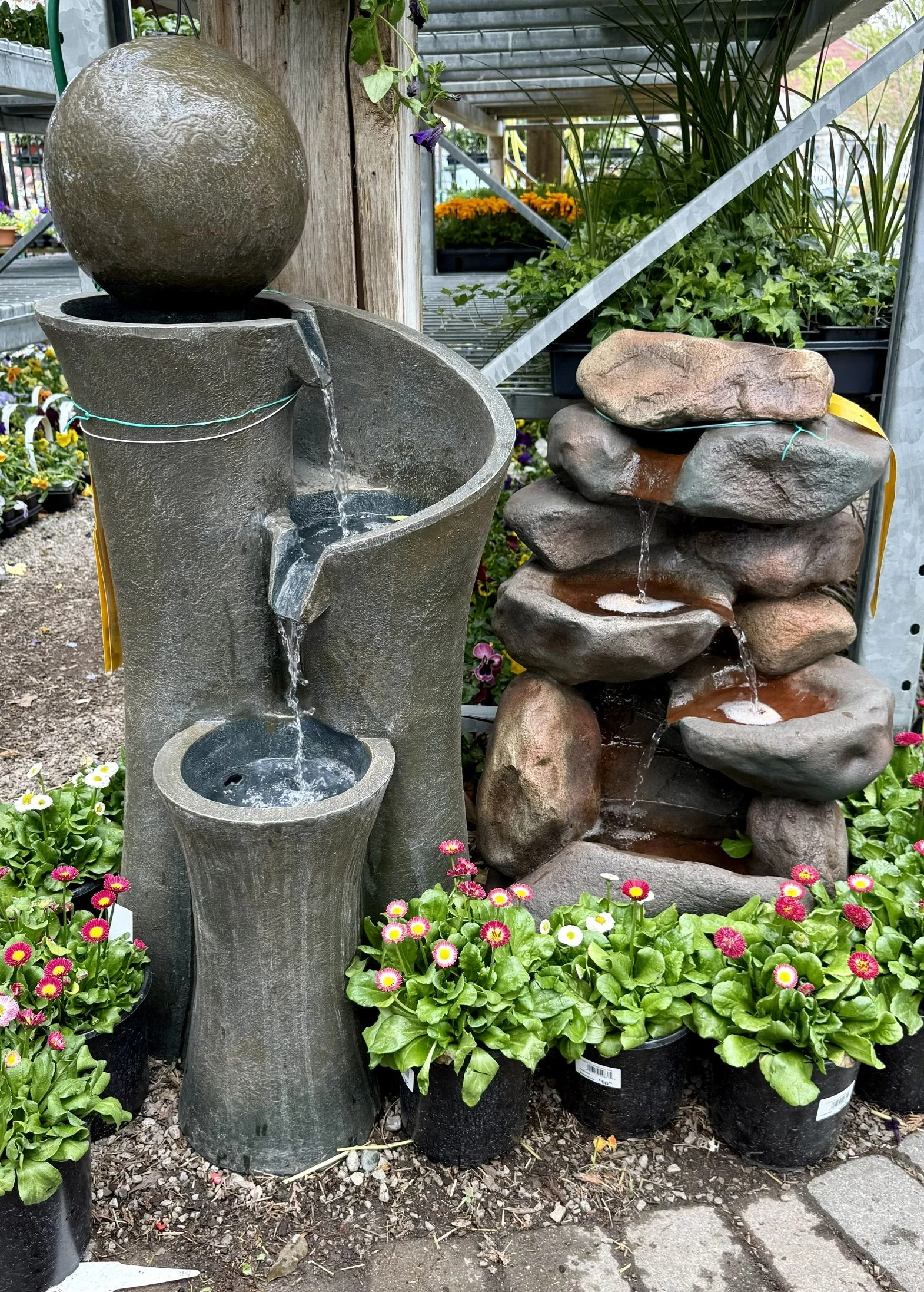 A decorative water fountain with a spherical top and a stacked stone water feature with water flowing over the rocks at Allemon’s Landscape Center, Detroit, Michigan serving the Grosse Pointe, St. Clair Shores, and Detroit Communities since 1929.