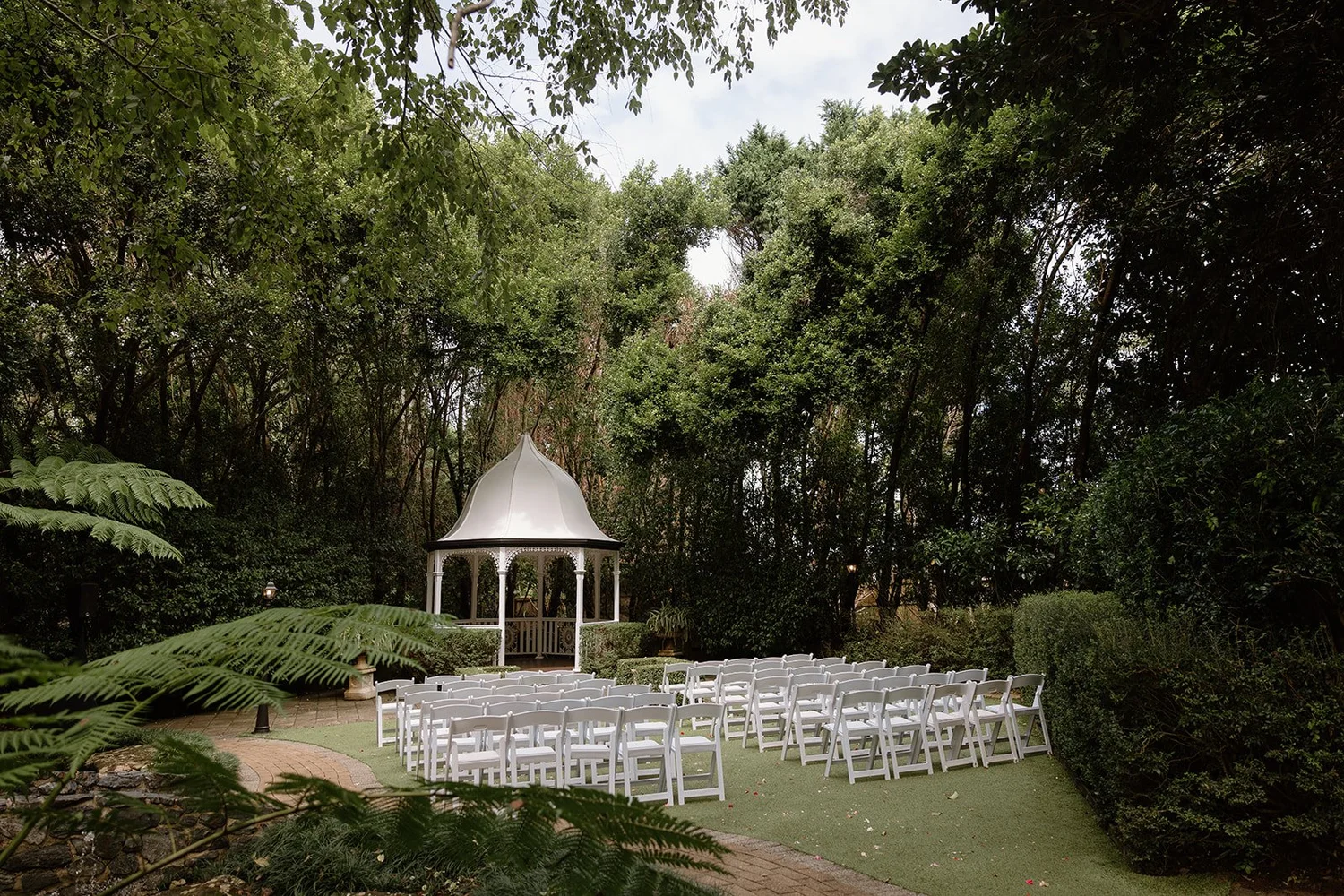 Outdoor garden wedding ceremony at Shambala Estate, with white gazebo and lush rainforest surrounds.