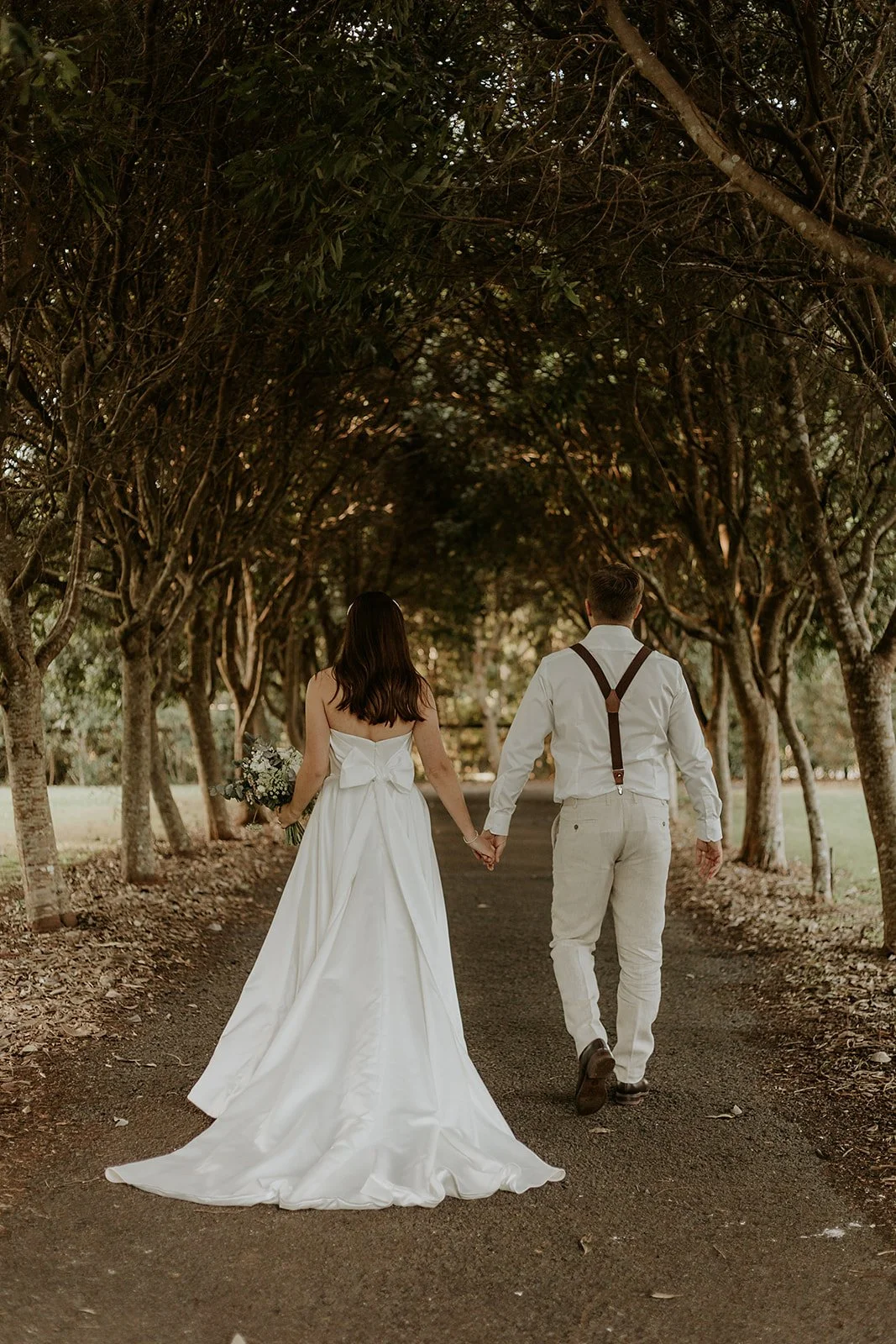 A couple walks beneath the tree-lined garden avenue at Shambala Estate on Tamborine Mountain.