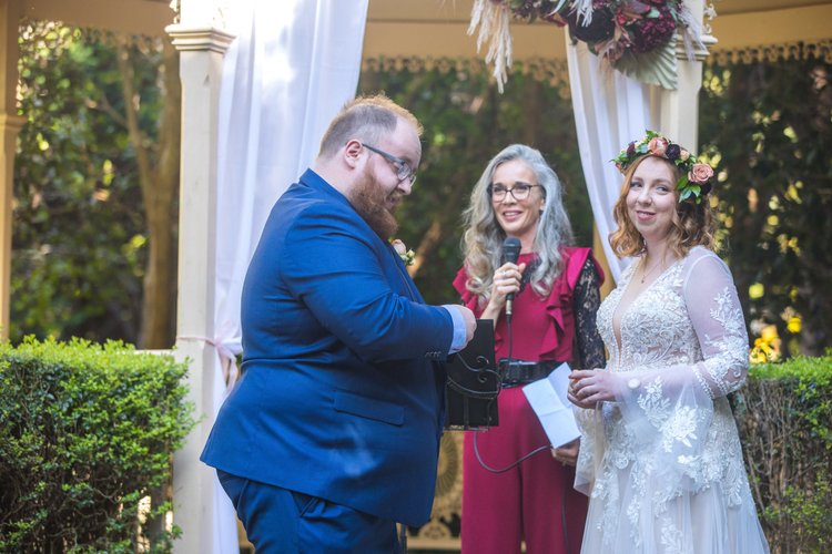 Tara Chapman speaking during Christina and Thomas Murray’s wedding ceremony at Shambala Estate, with the couple beside her.