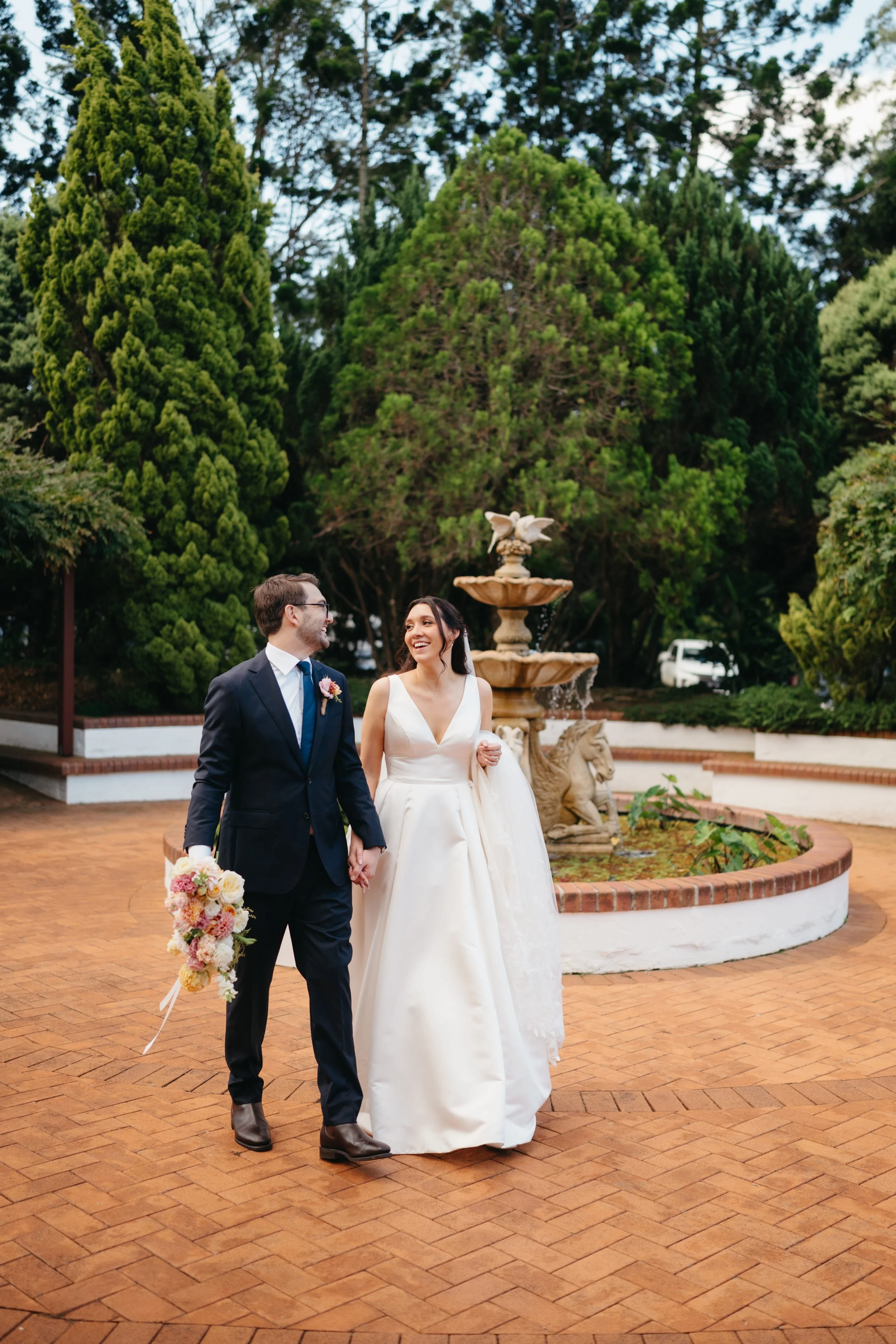A newly married couple walking beside Shambala Estate's garden fountain