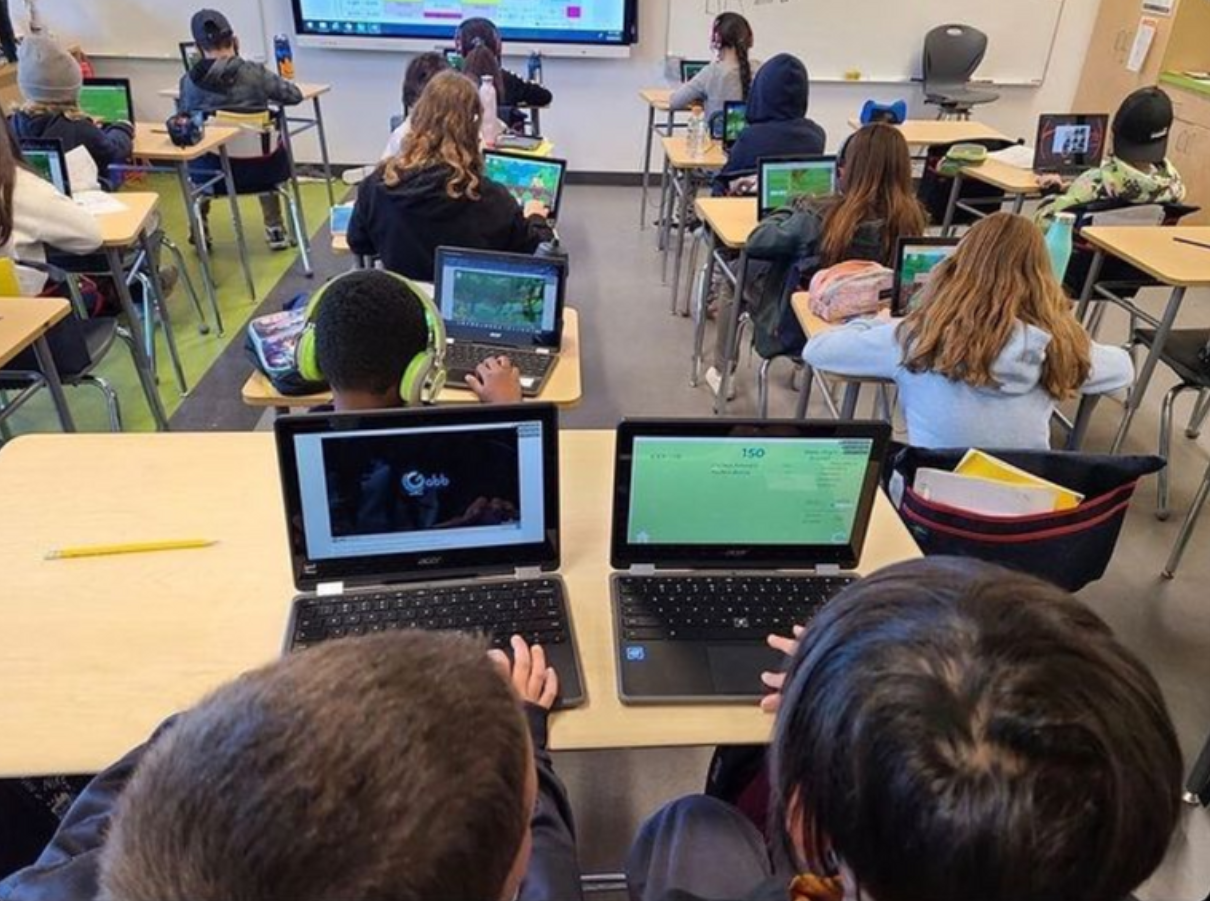 Classroom full of students working on laptops at their desks.