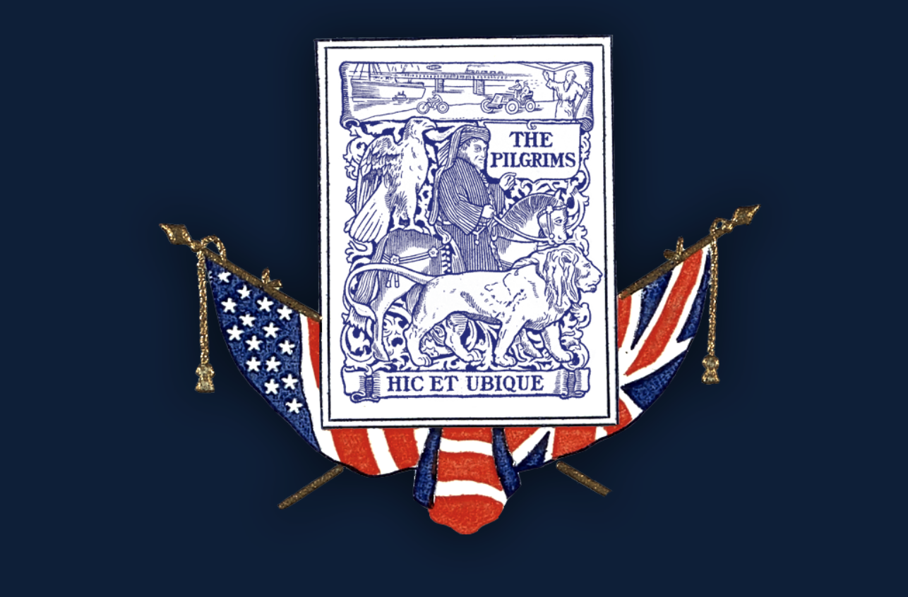 A badge with a navy blue background featuring a depiction of The Pilgrims, a lion, a dog, and a horse. The badge is adorned with American flag motifs and includes the Latin phrase 'Hic et Ubique.'