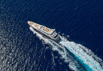 A large yacht sailing on the open ocean, creating a wake behind it.