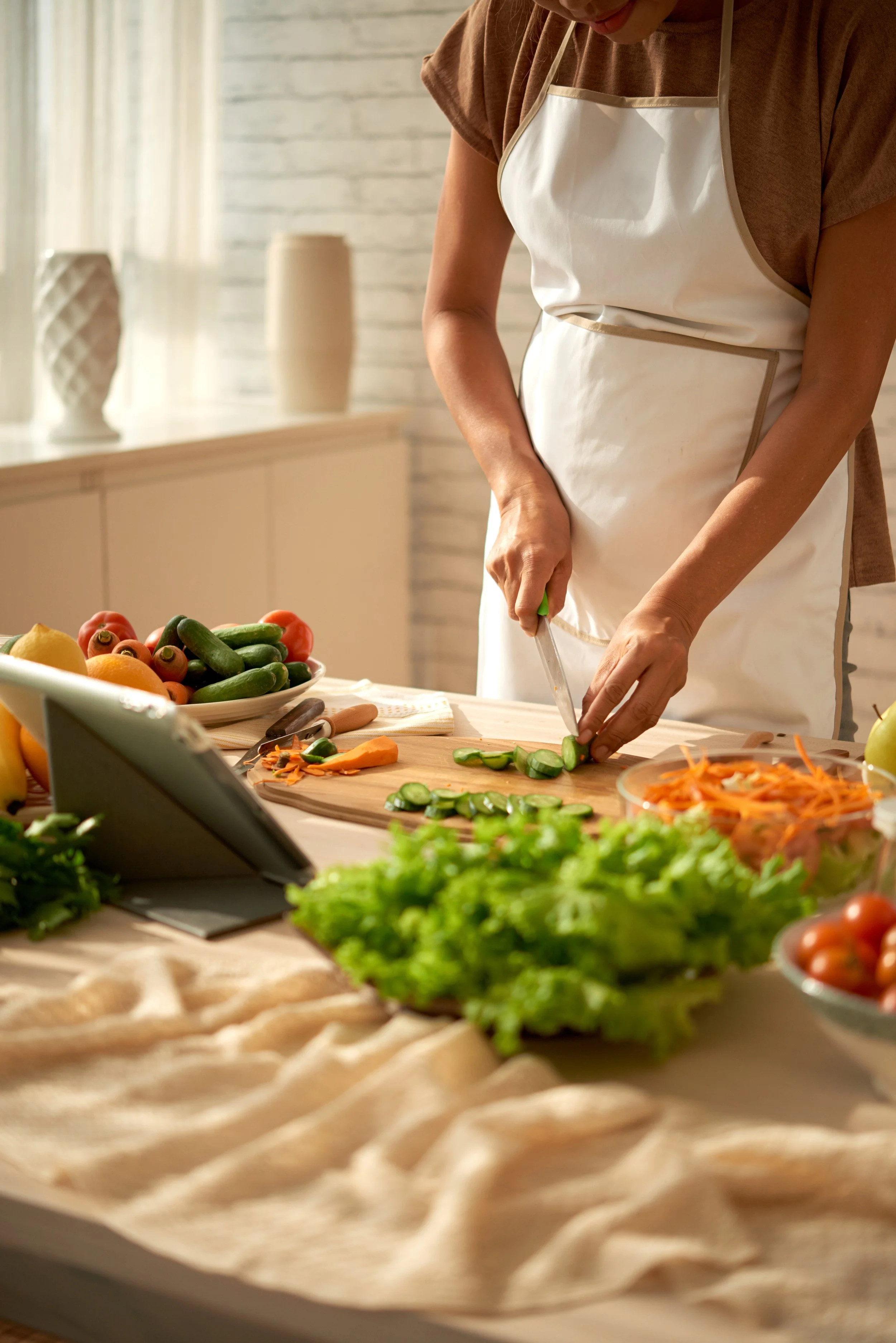 Personne préparant une salade avec des légumes coupés dans une cuisine lumineuse.