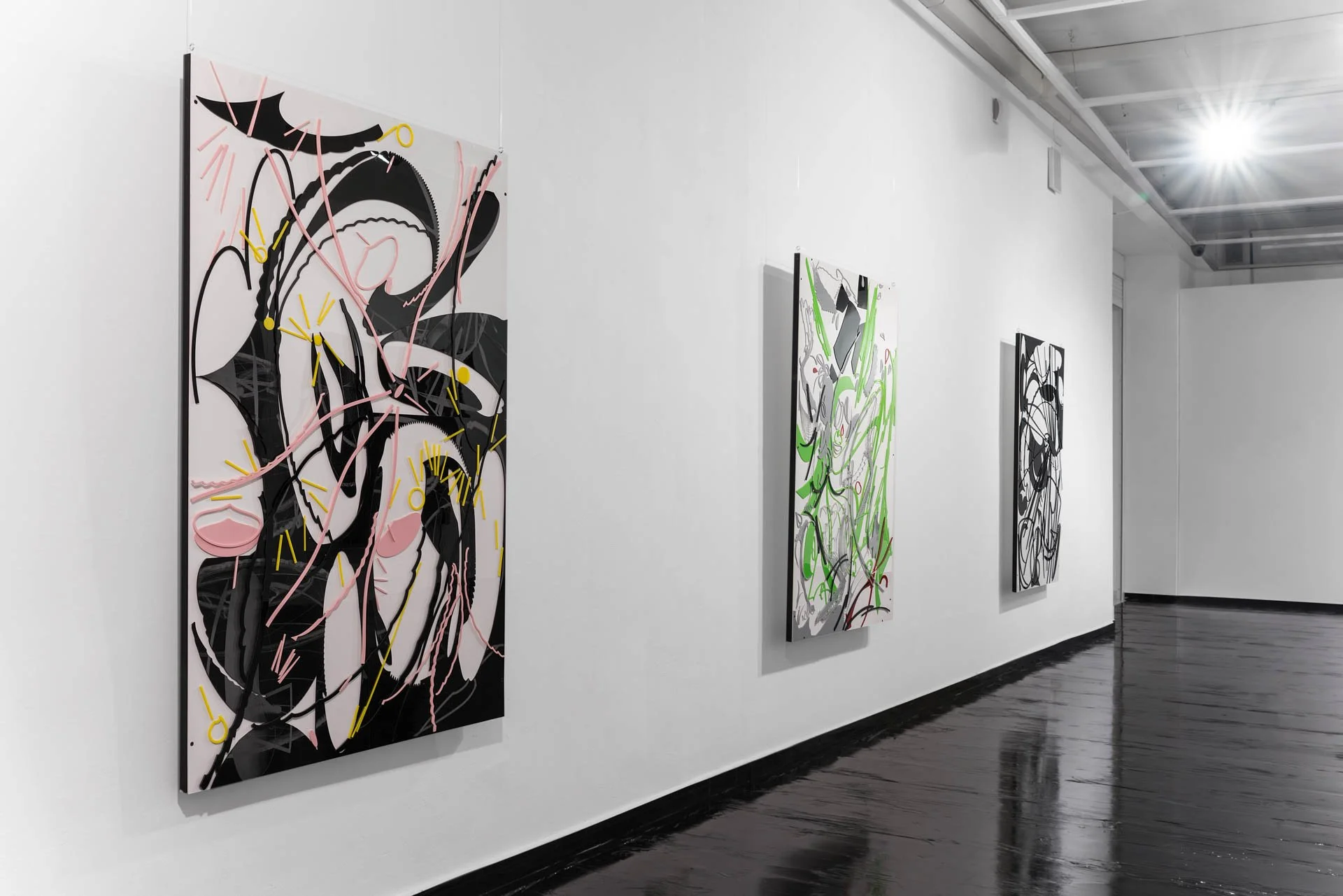 Gallery with three abstract paintings on white walls in a modern art gallery, with black polished floors and bright ceiling lights.