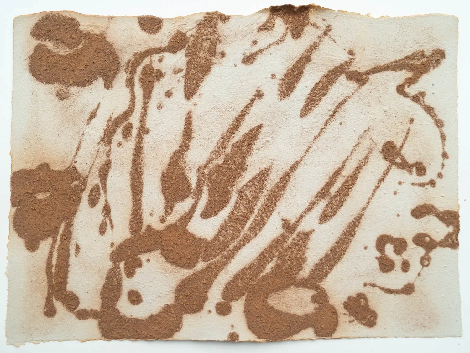 Powdered cocoa or cinnamon sprinkled on a flat surface in a random, abstract pattern.