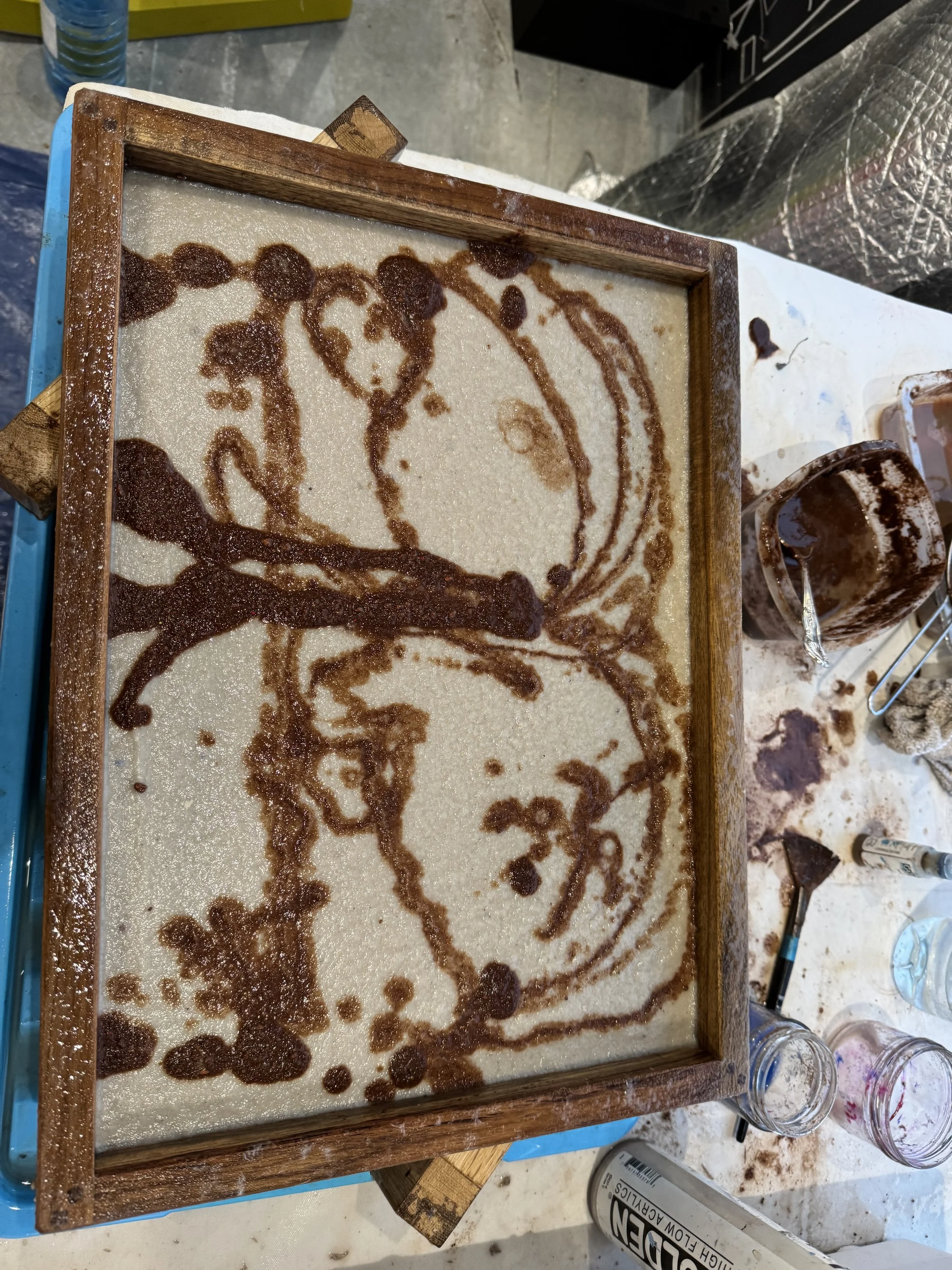 Sand art in a wooden frame depicting a butterfly with a smiling face.