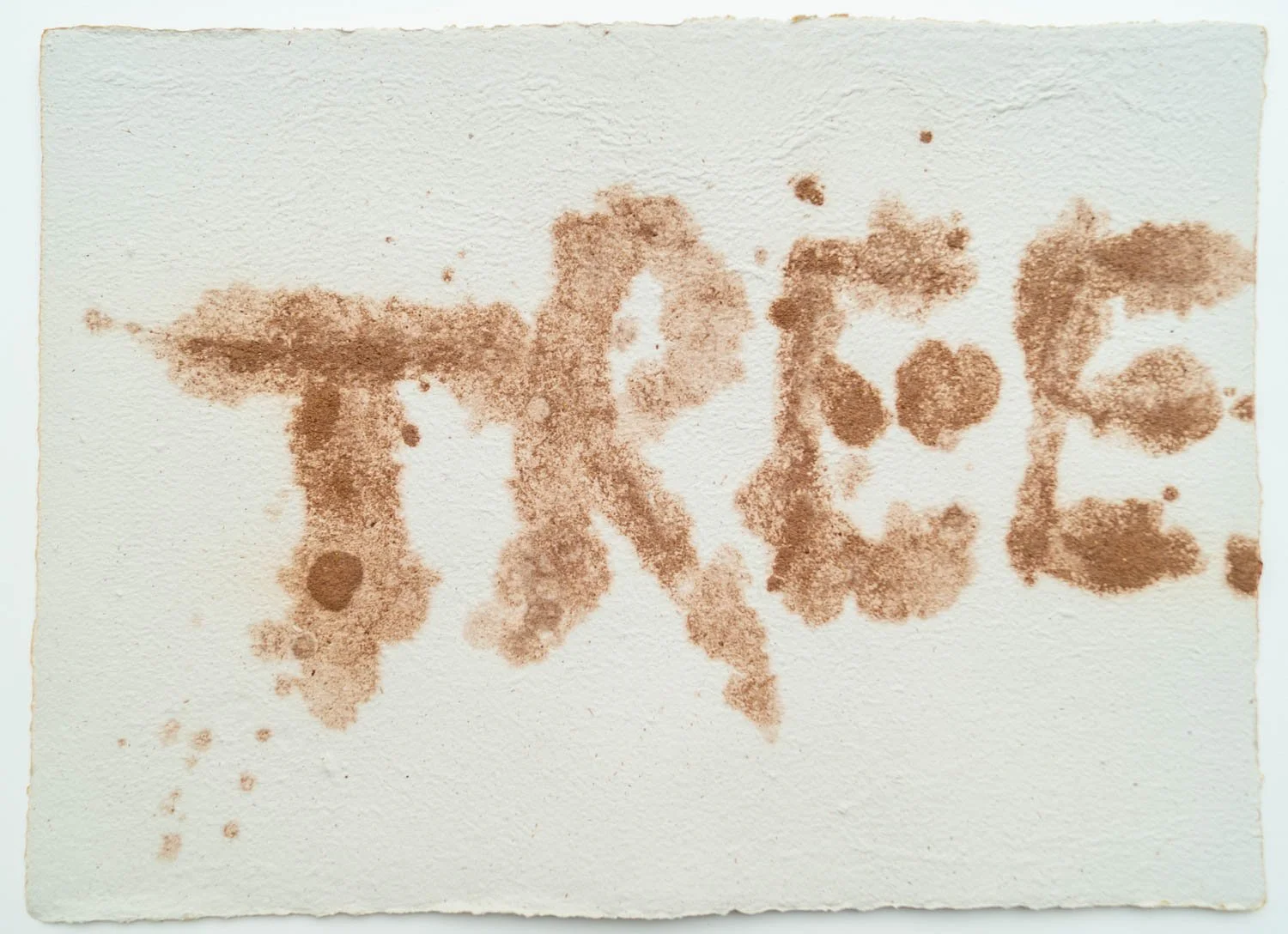 The word 'love' spelled out with coffee or tea stains on a white piece of paper.