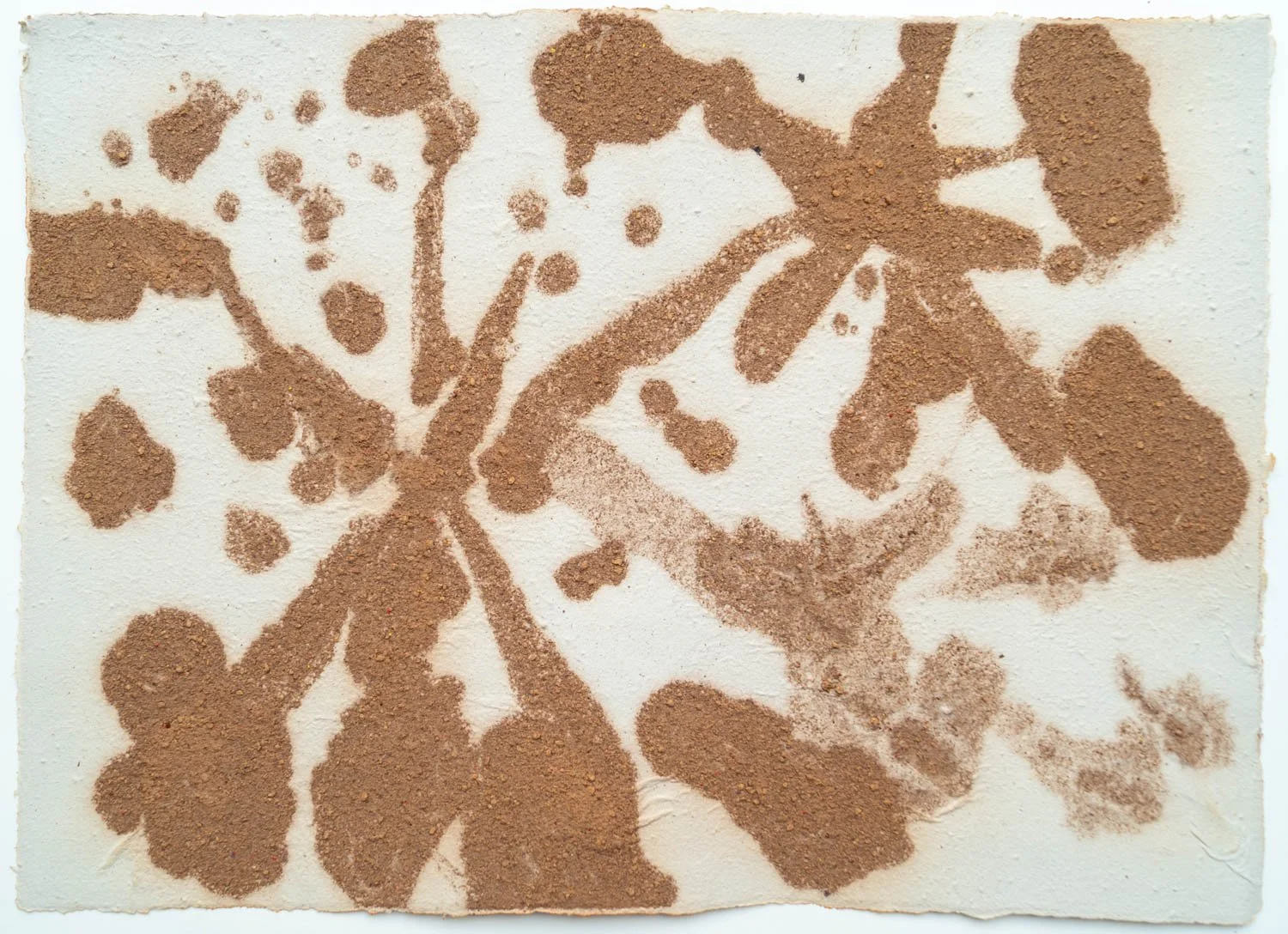 A butterfly shape is created by sprinkling brown powder on white paper.