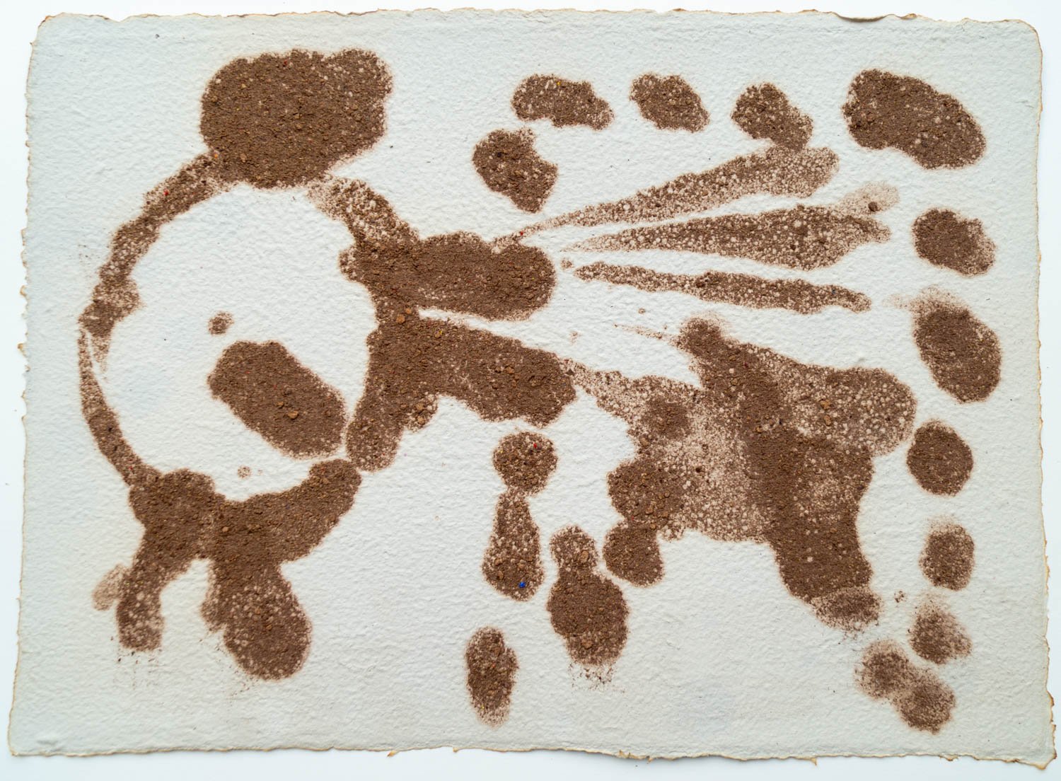 Sand art depicting a dog with a ball in its mouth, surrounded by paw prints.