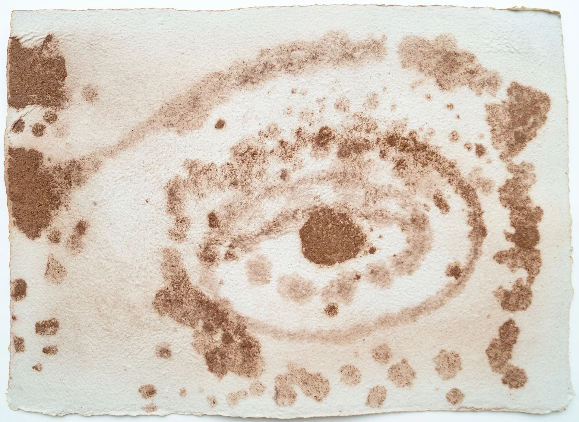 Sepia-toned, abstract spiral pattern on textured paper, with scattered dots around it.