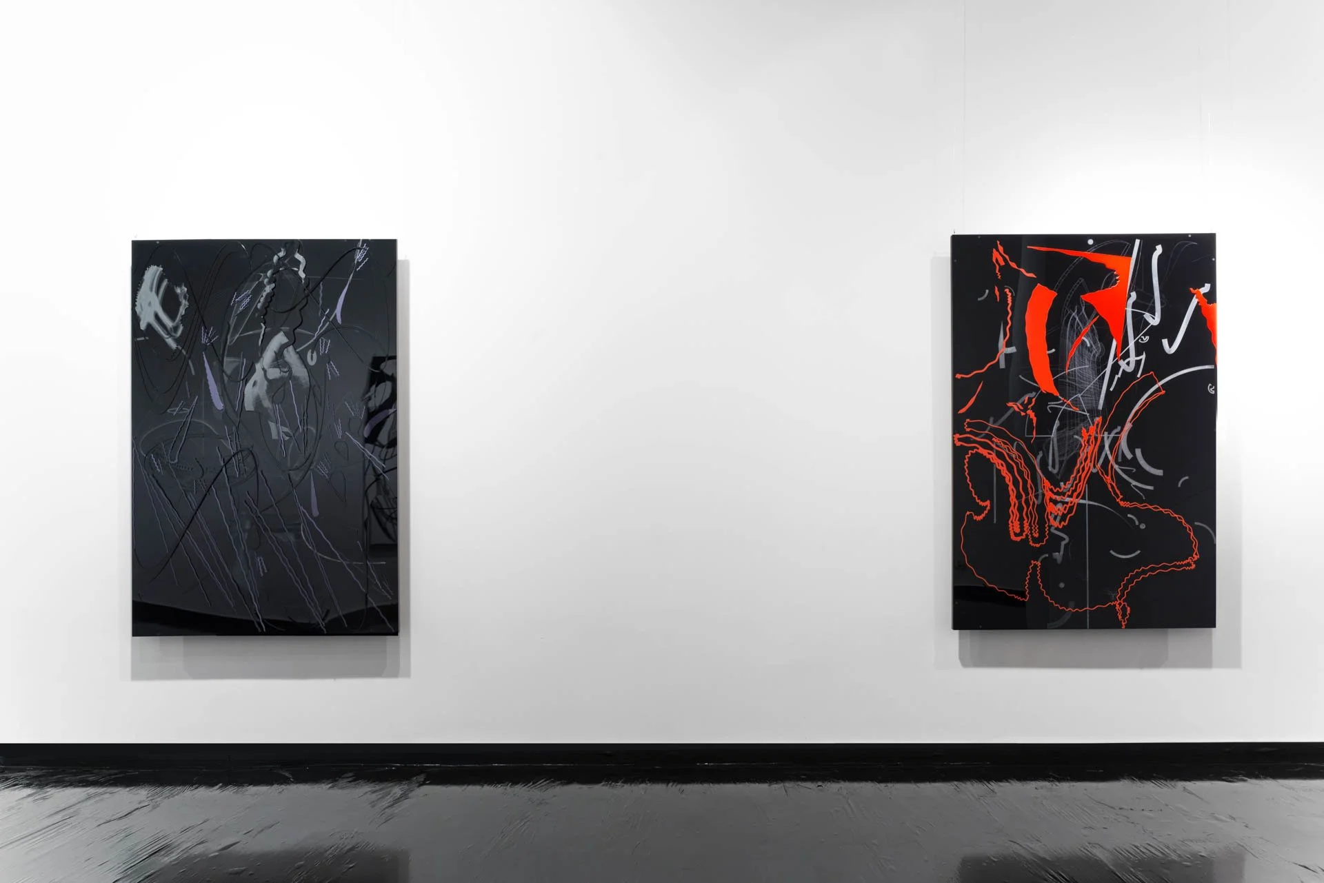 Two abstract paintings on a white gallery wall, one with dark background and lines, the other with black background and red and white shapes.