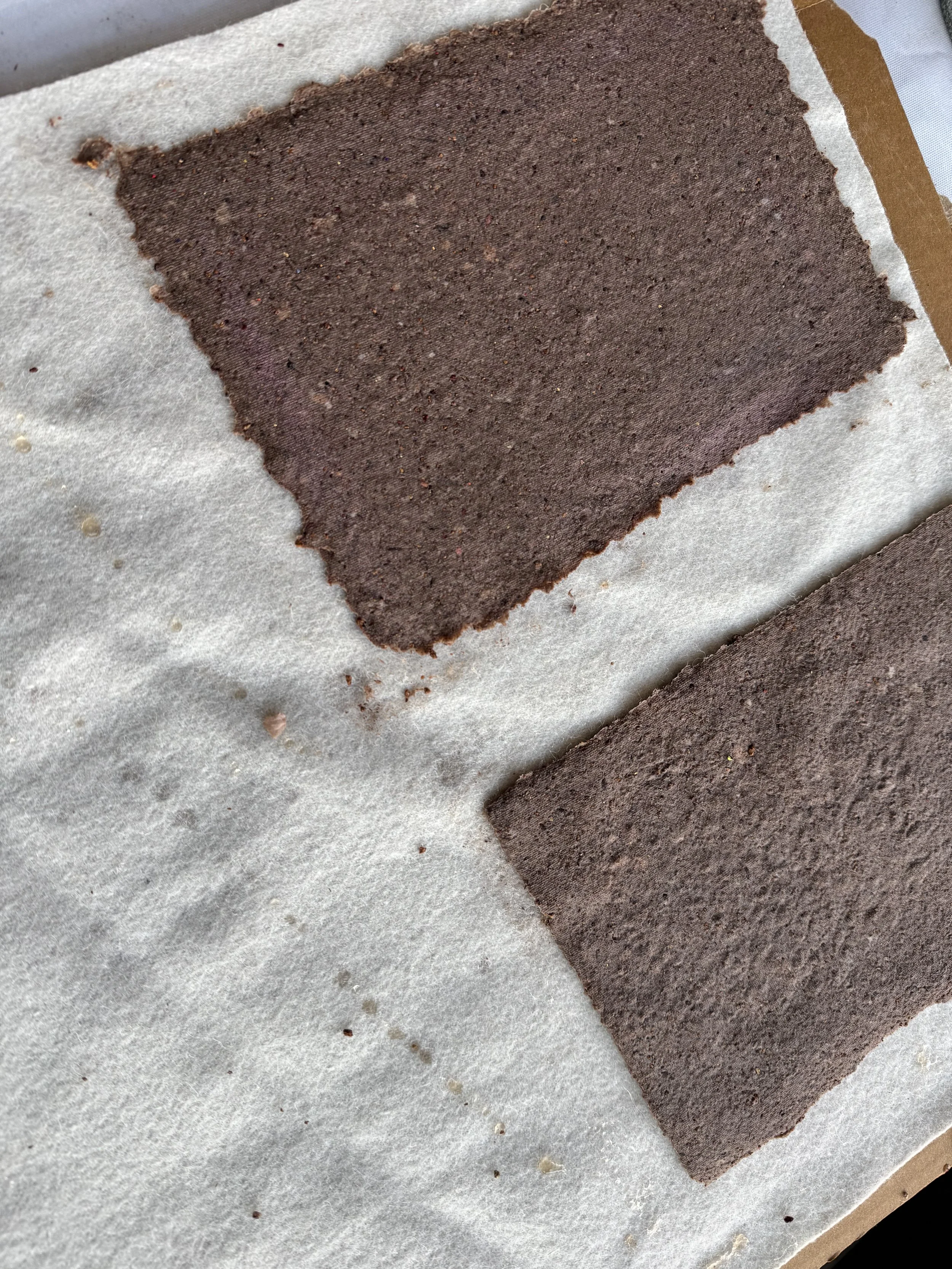Two rectangles of baked chocolate cake on parchment paper.