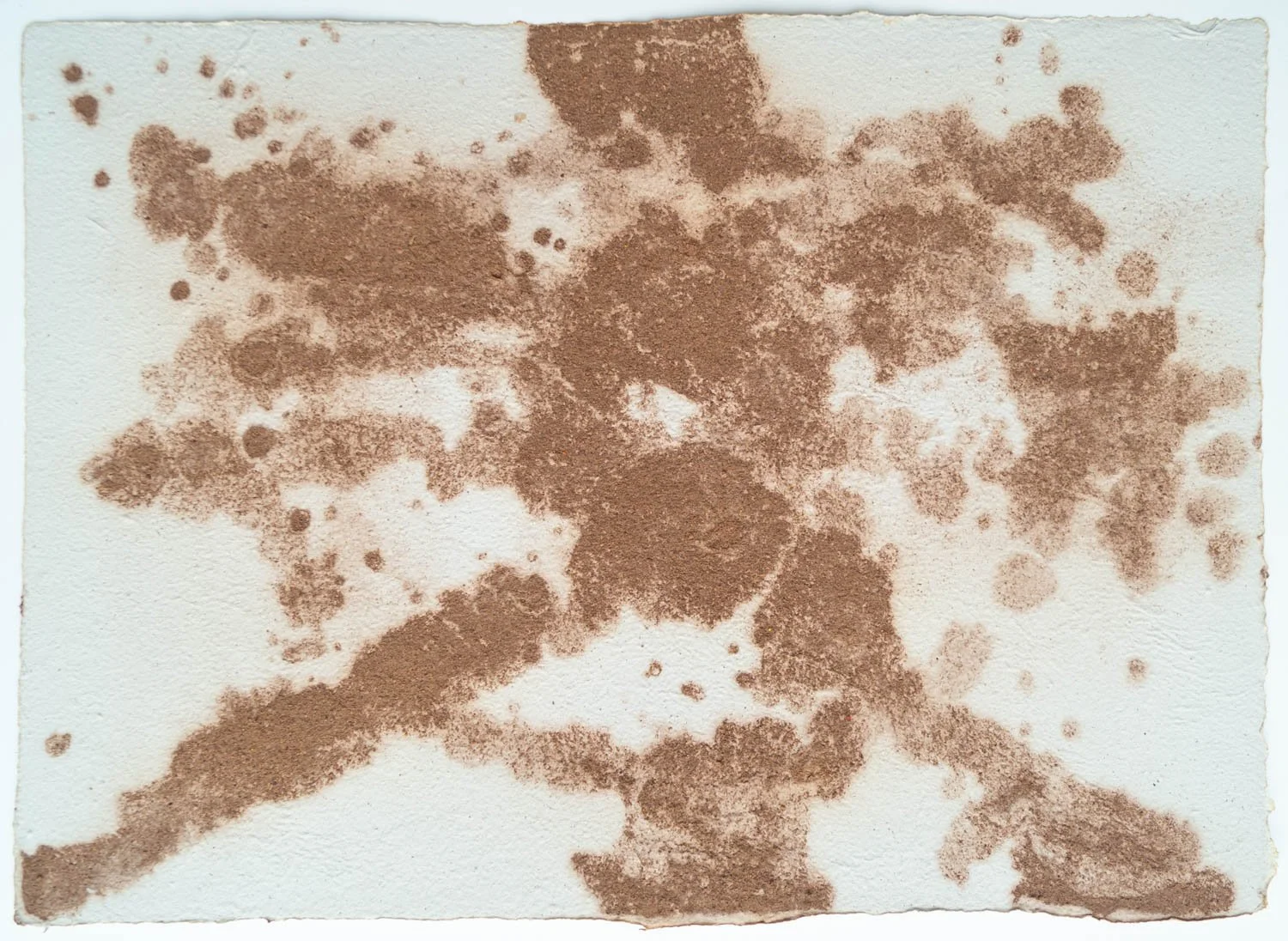 Abstract brown ink splatters on white textured paper
