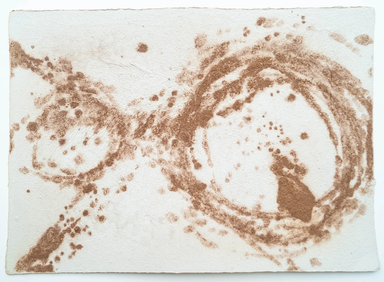 Sand art of a dog sitting inside a circular outline, with an arrow pointing to the left, on a white background.