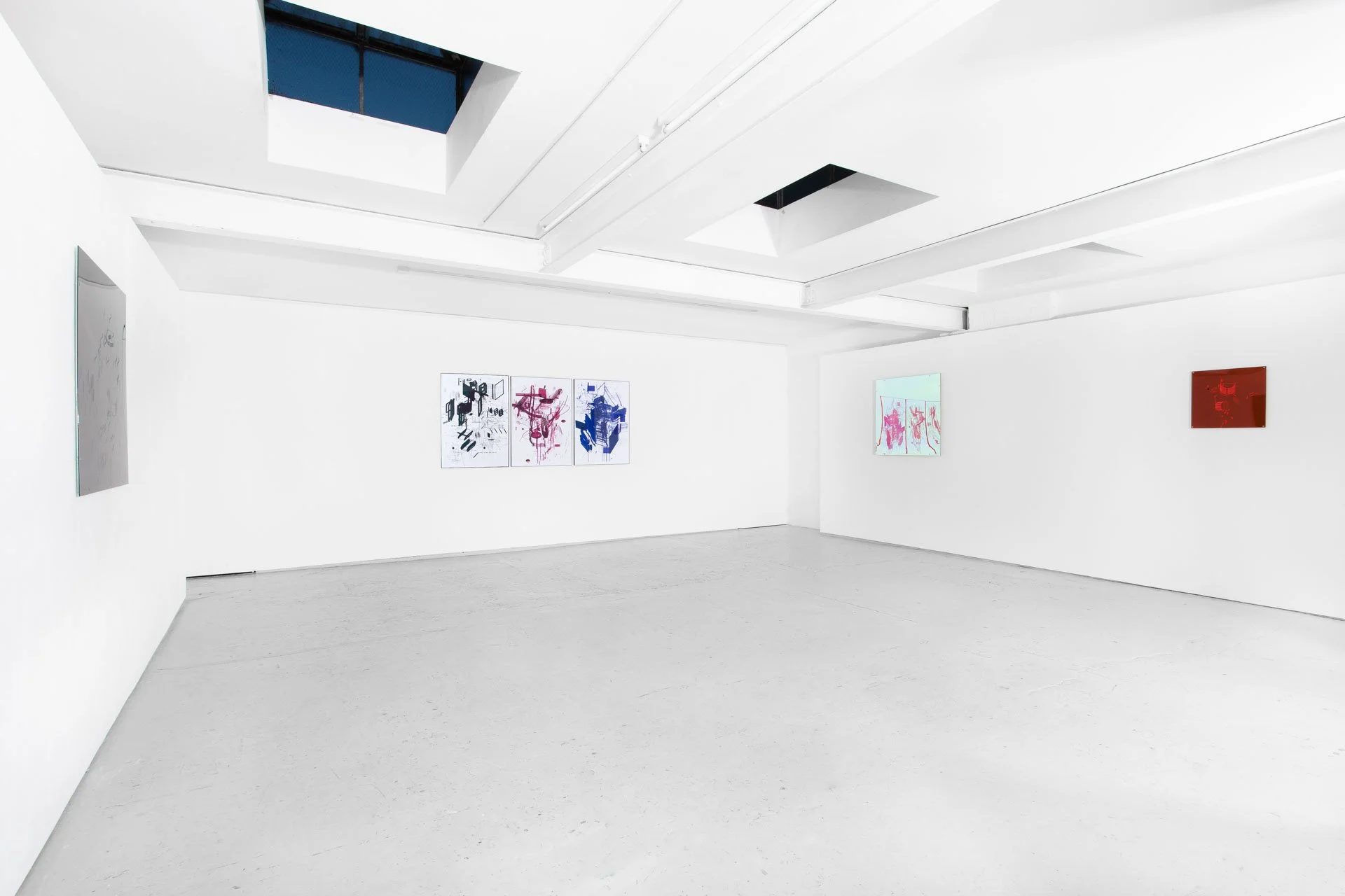Art gallery with white walls displaying abstract paintings, a white ceiling with skylights, and a light-colored floor.