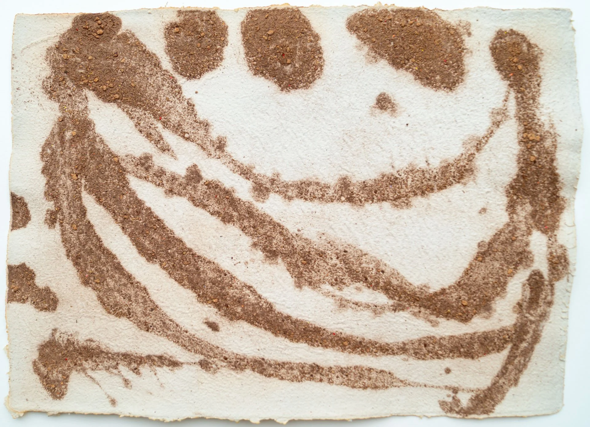 A piece of paper with a smiley face and a swirl, created by scattering cocoa powder or cinnamon on a white surface to form the design.