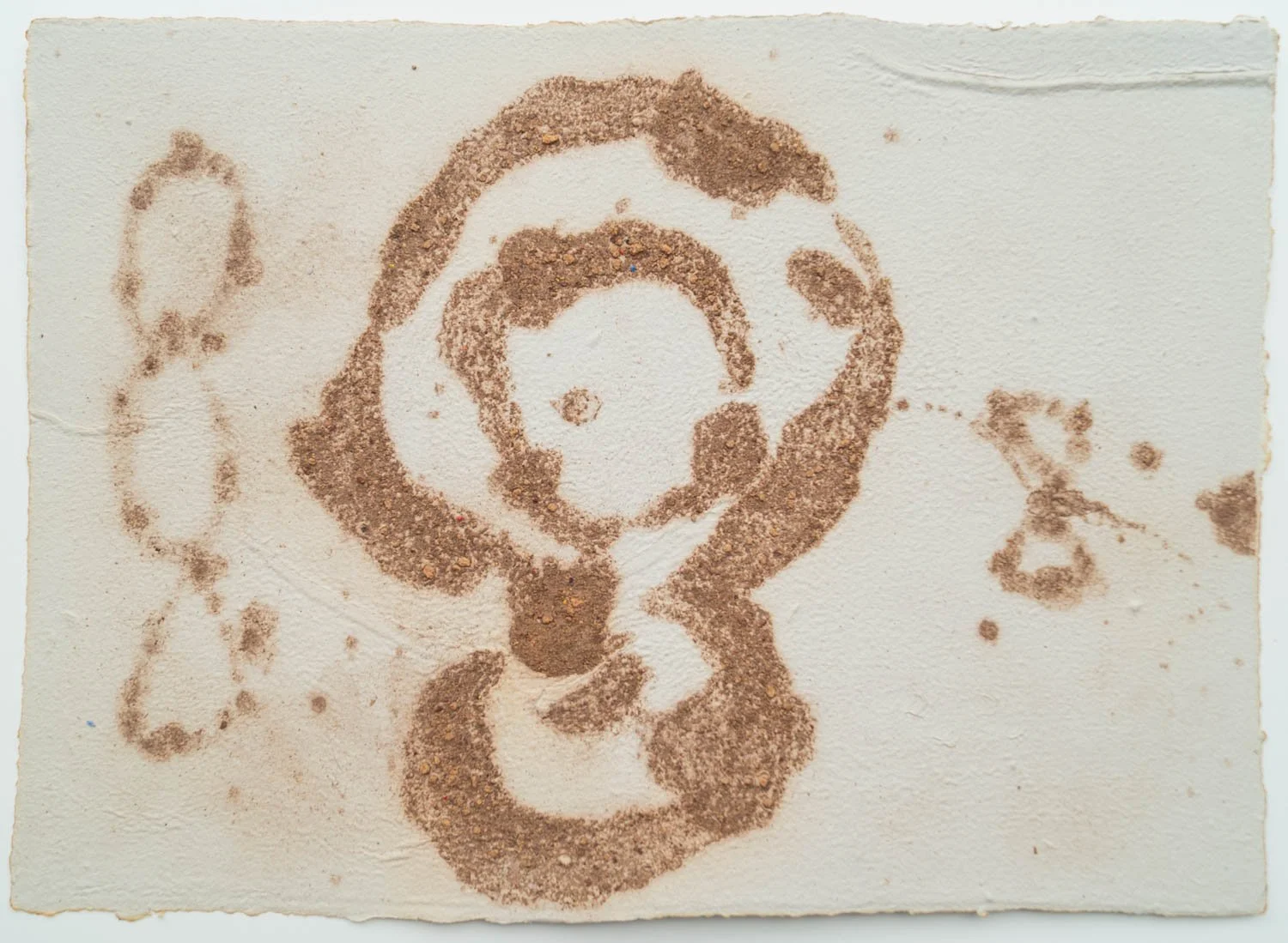 Sand art depicting a woman's face, surrounded by flowers, made on a textured white surface.