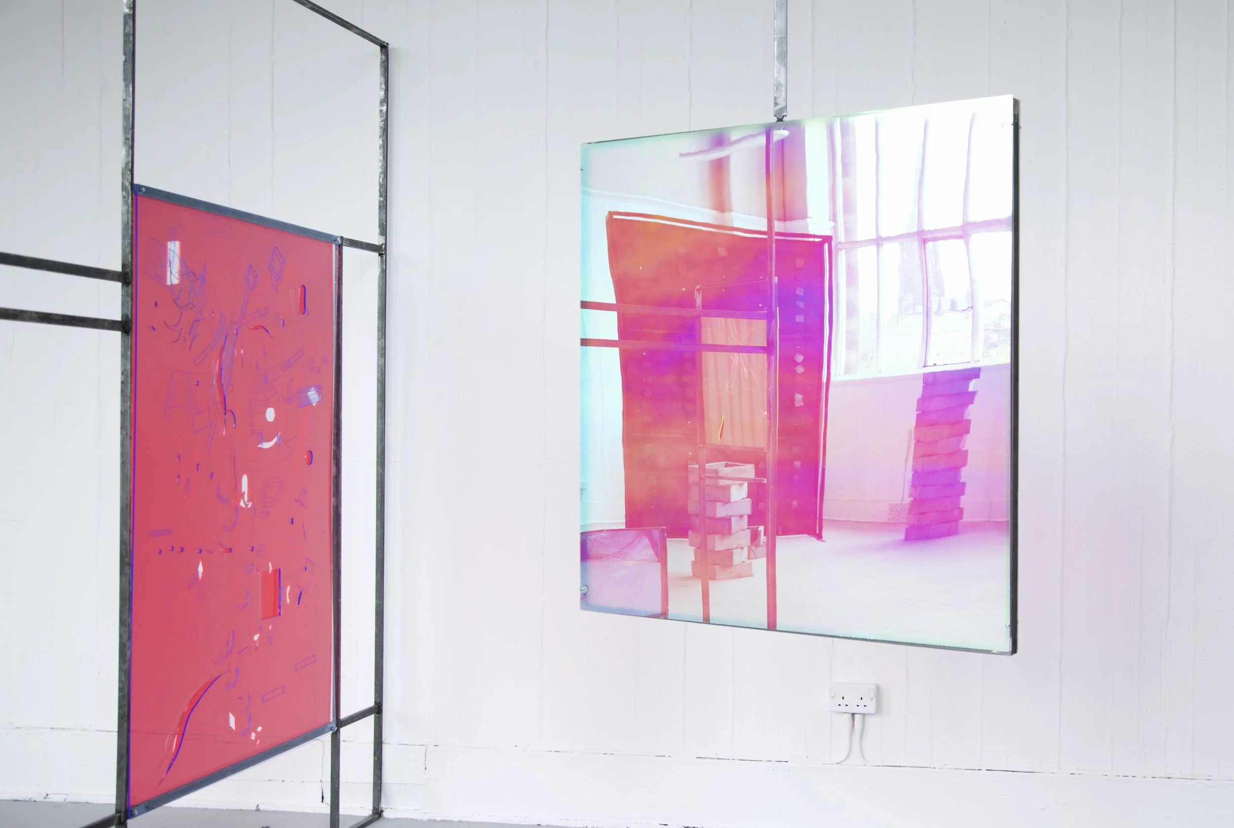 Contemporary art installation featuring two large digital screens with colorful, abstract visuals in a gallery setting