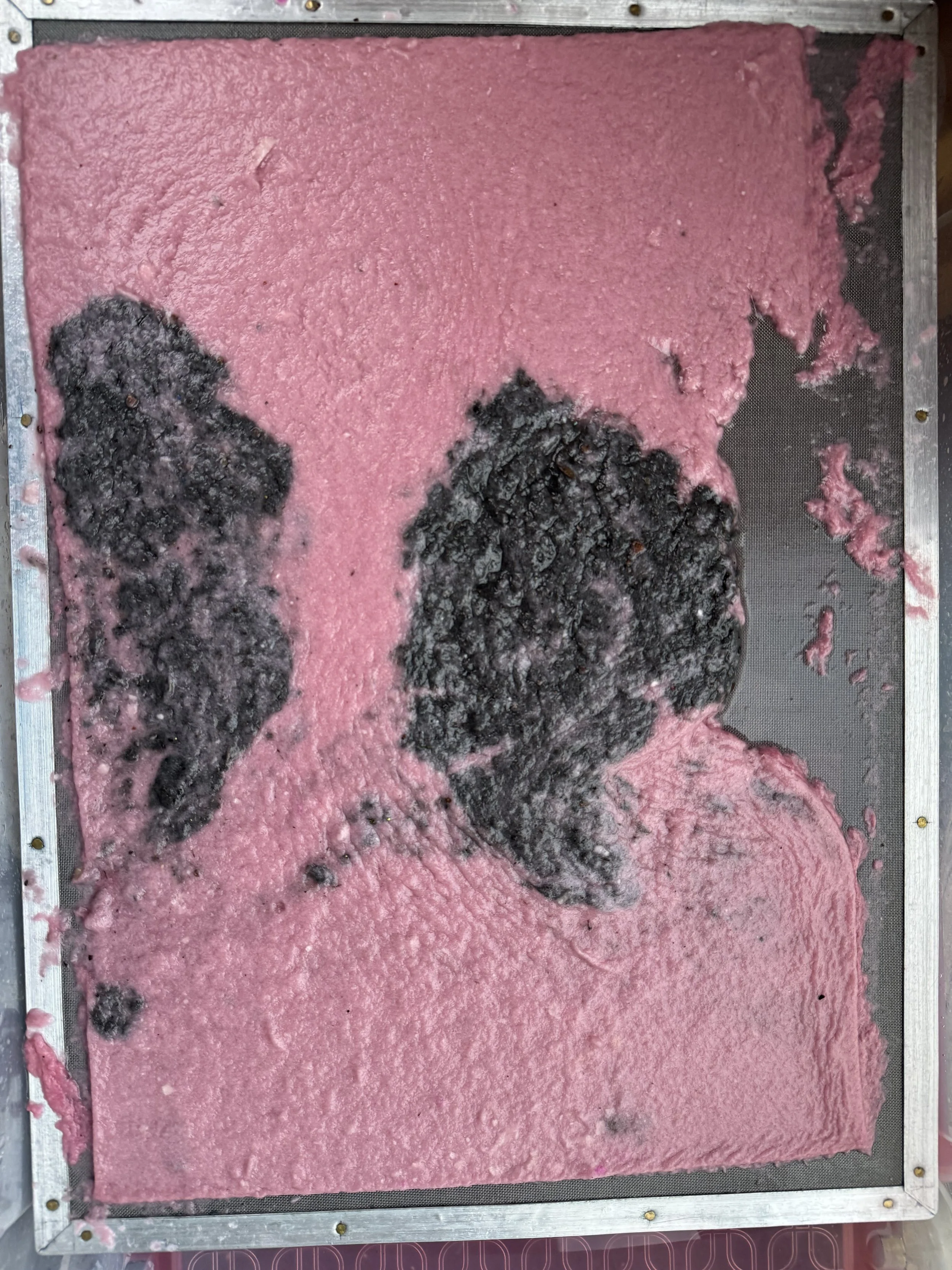 Pink cotton candy with black burnt sugar on a metal tray.