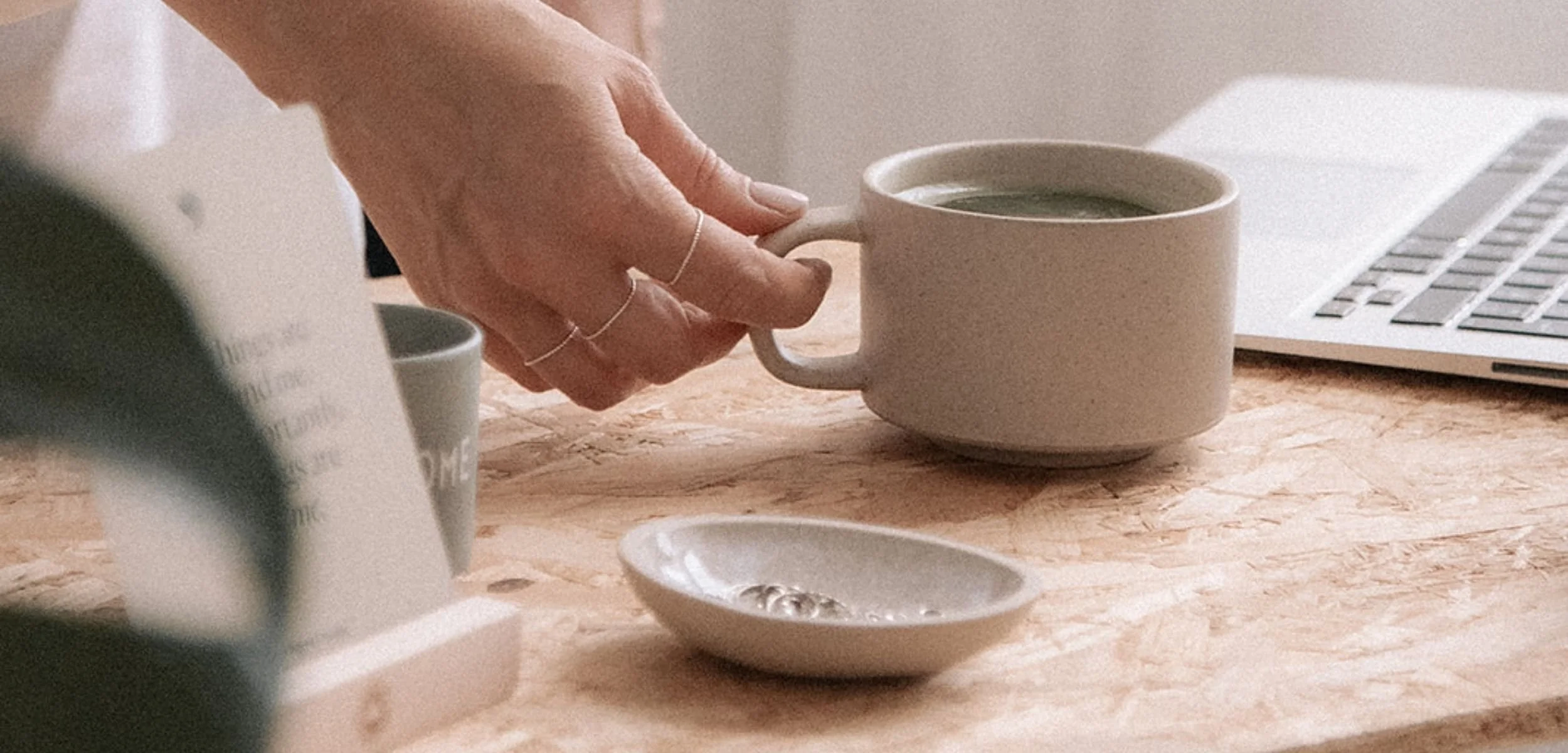 Työpöytä, käsi, joka pitää kiinni teekupin korvasta. Ratkaisukeskeinen valmennus online tai Helsinki